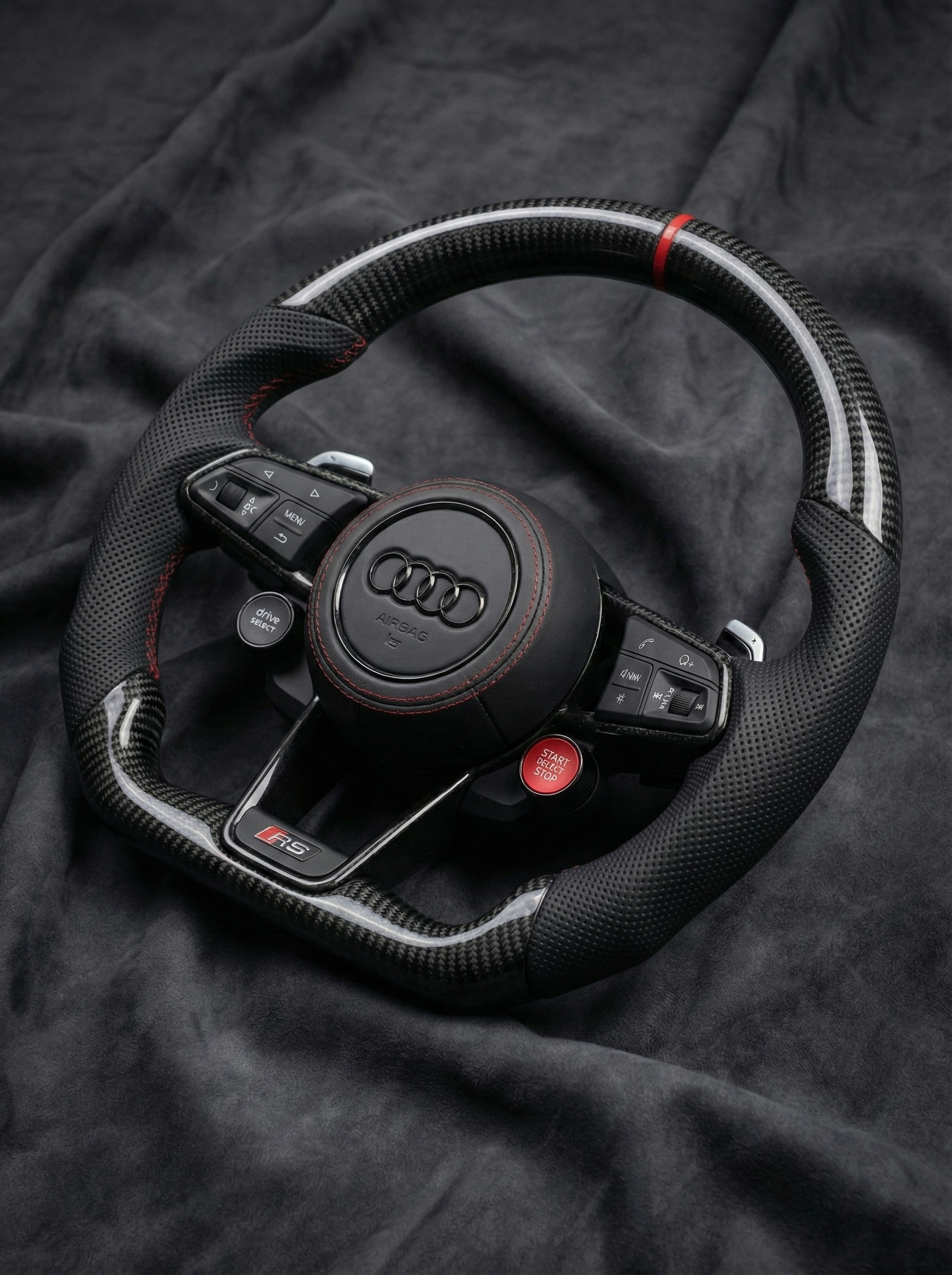 Black Audi steering wheel on a dark fabric background