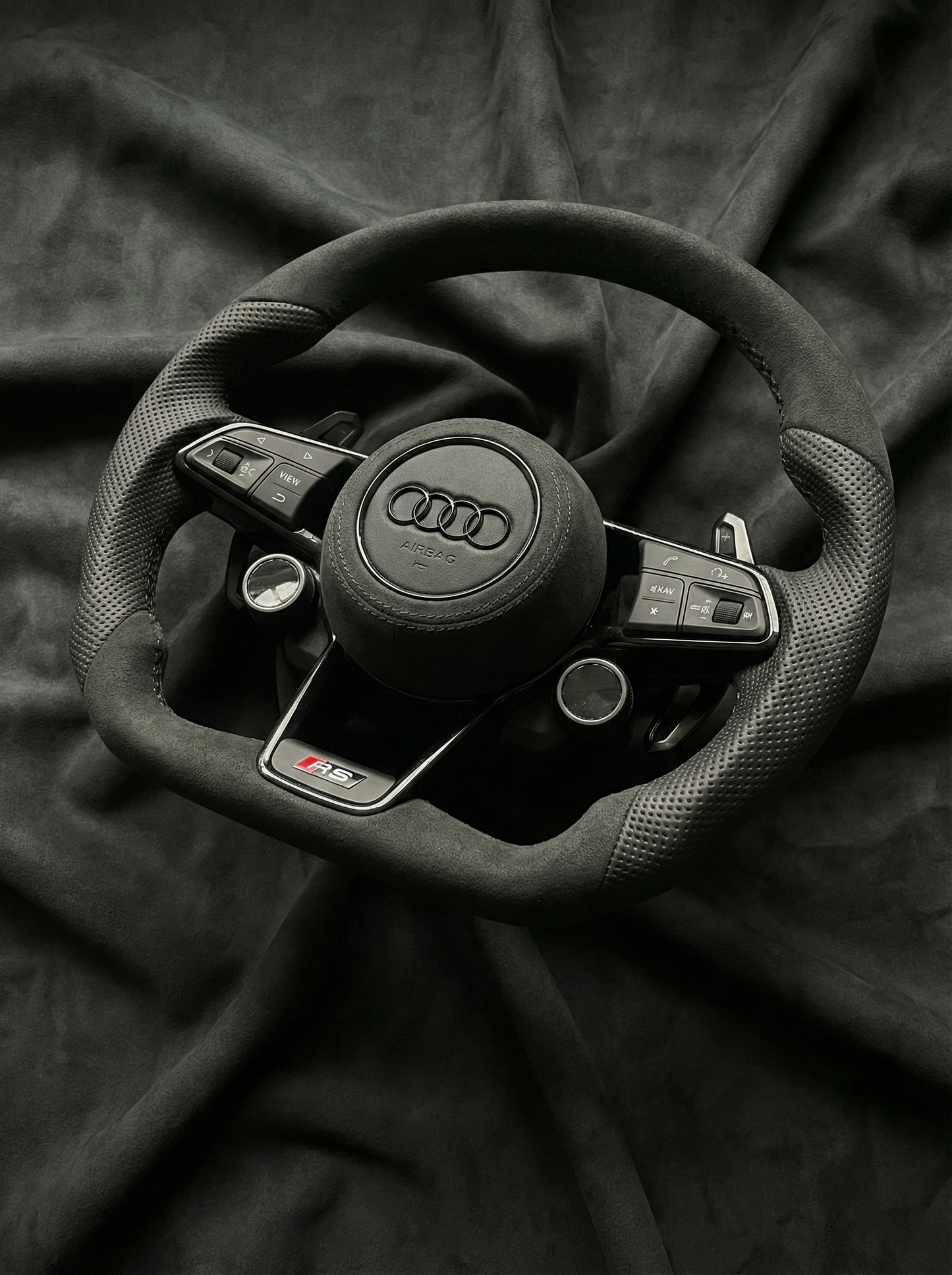 Steering wheel with Audi logo on a dark fabric background
