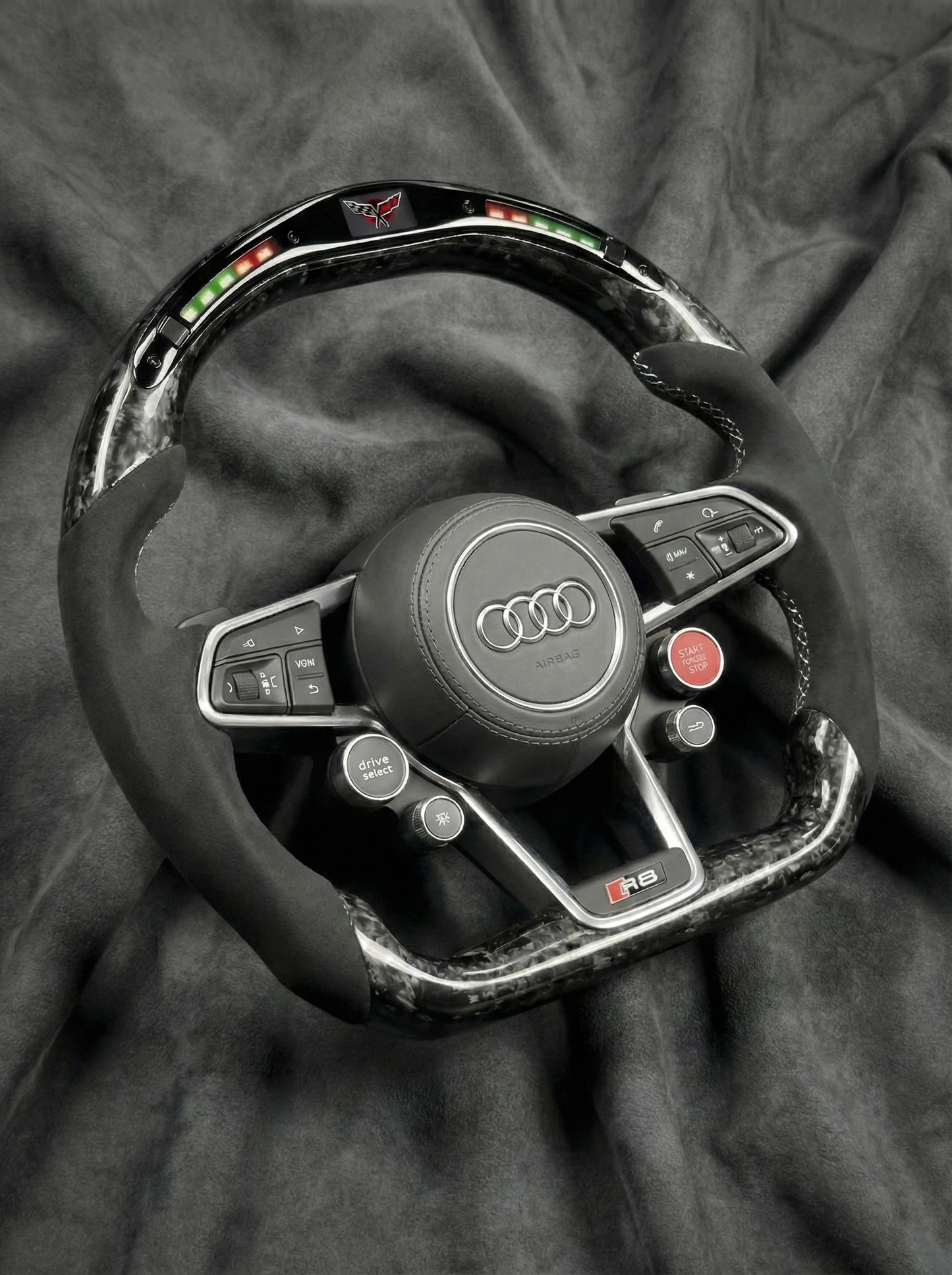 Steering wheel with Audi logo on a dark fabric background
