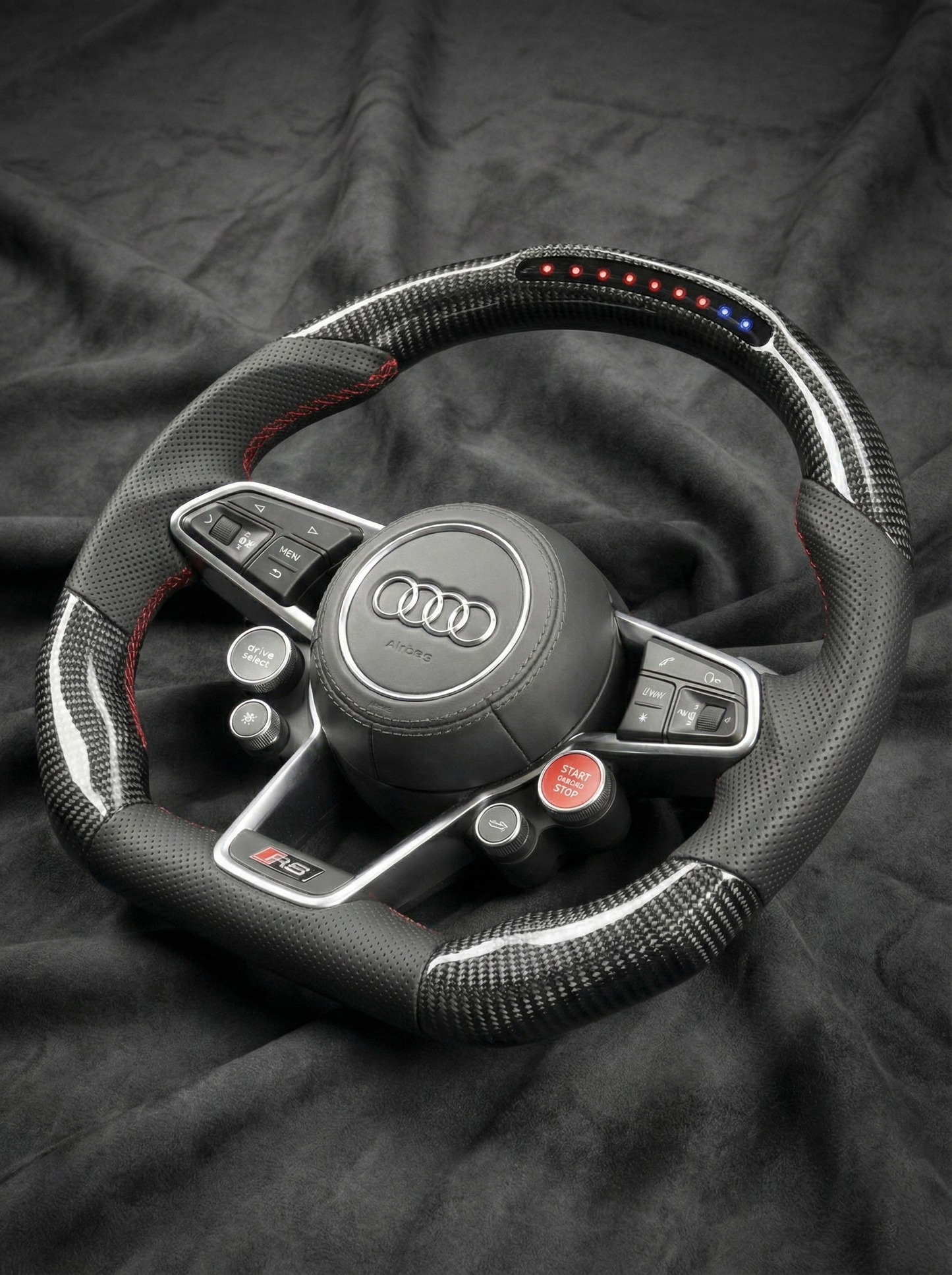 Steering wheel with Audi logo on a dark fabric background