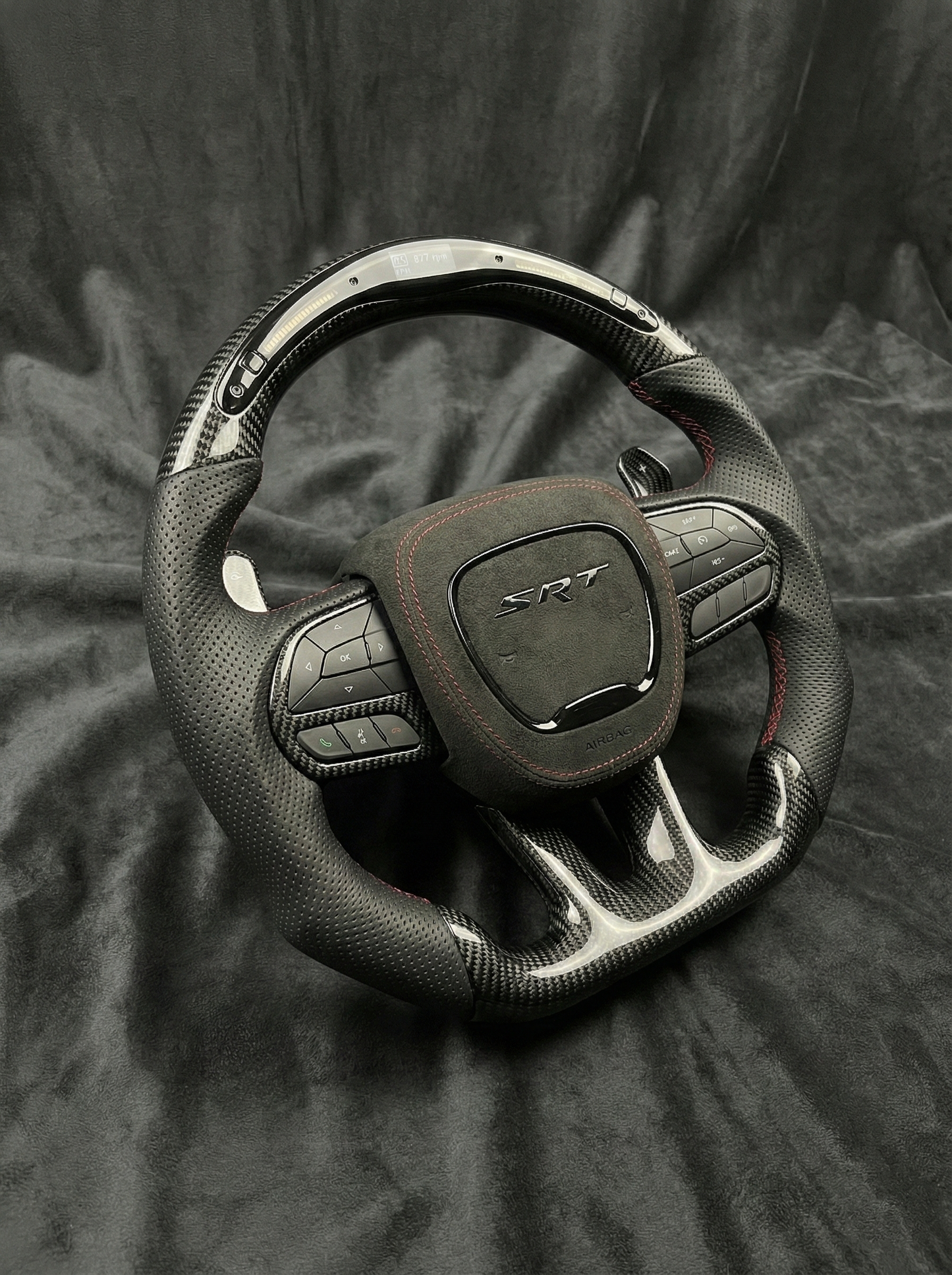 Car steering wheel with SRT logo on a dark fabric background