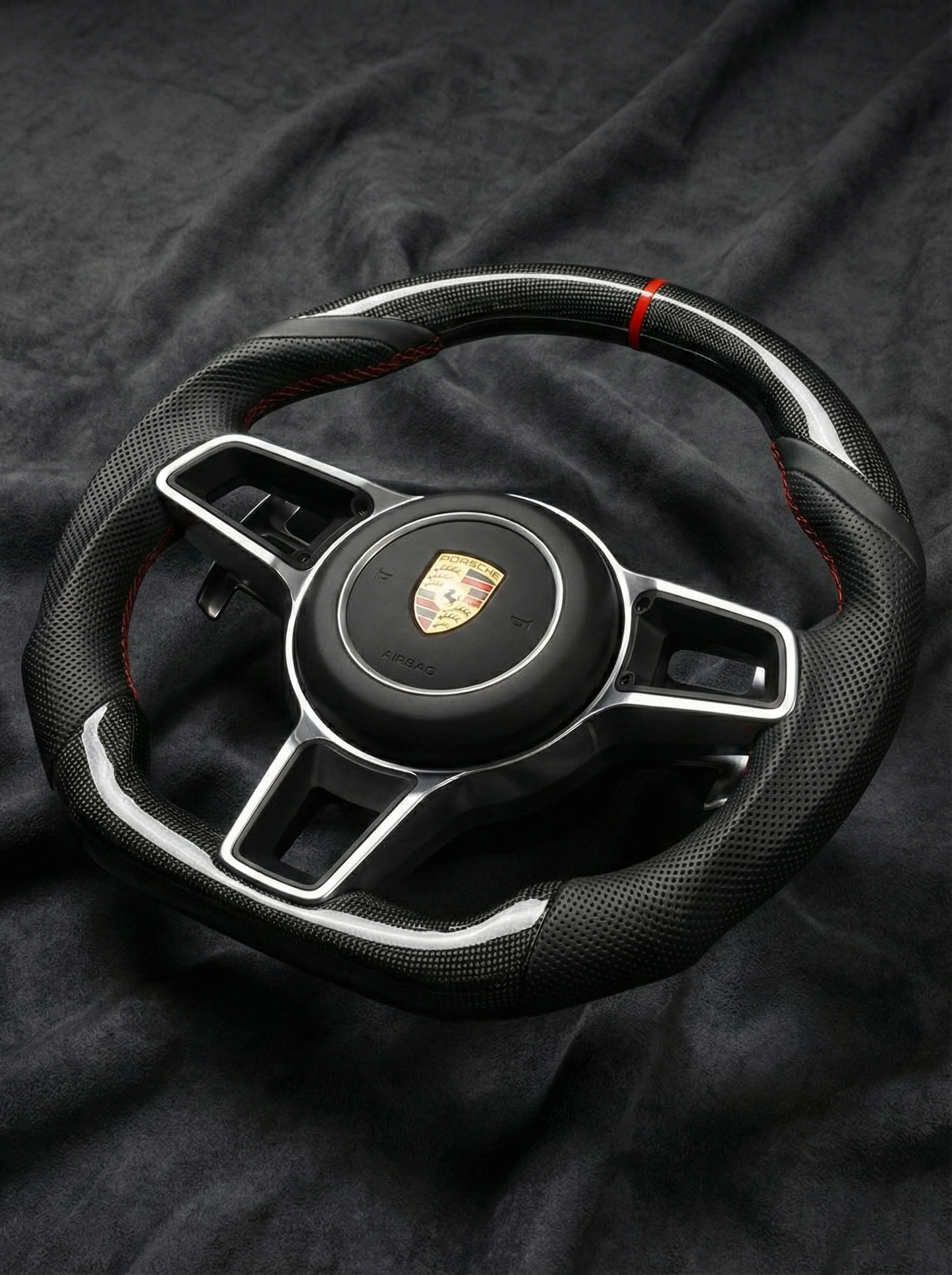 Steering wheel with Porsche logo on a dark fabric background