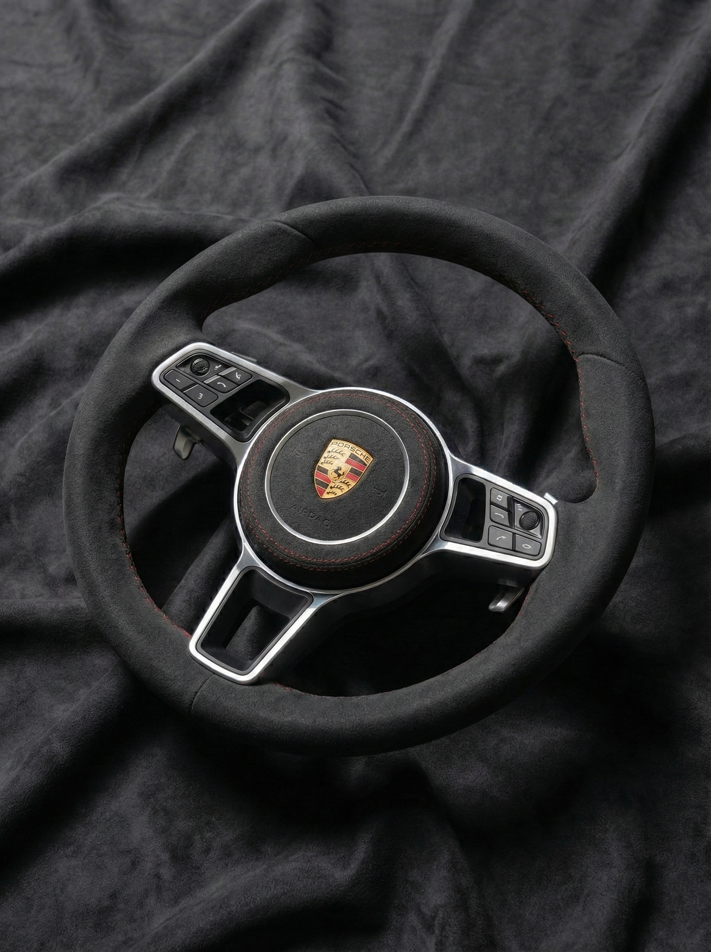Steering wheel with Porsche logo on a dark fabric background