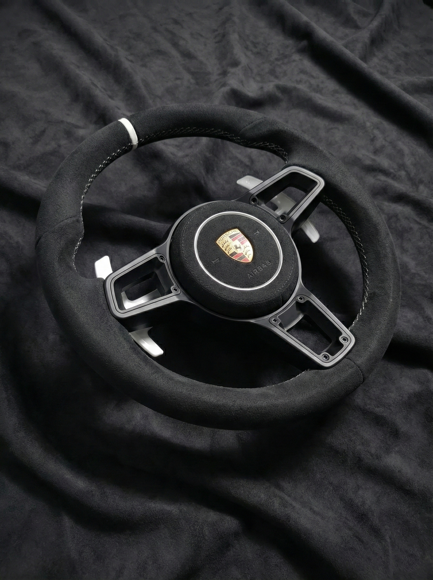Steering wheel with Porsche logo on a black textured background