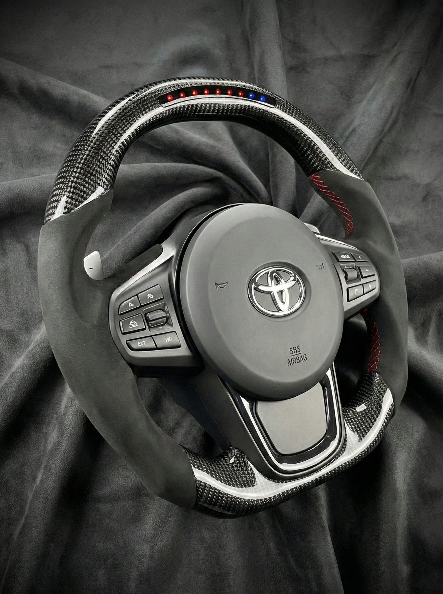 Car steering wheel with Toyota logo on a dark fabric background