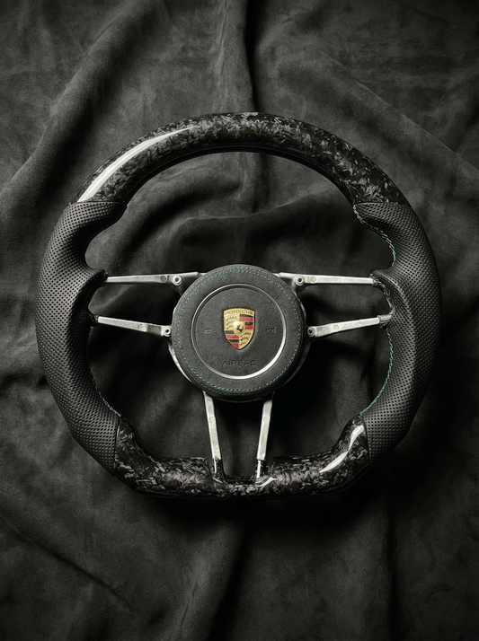 Steering wheel with Porsche logo on a dark fabric background