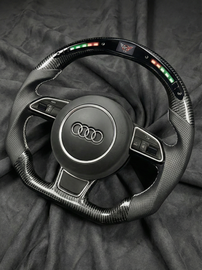 Carbon fiber steering wheel with Audi logo on a dark background