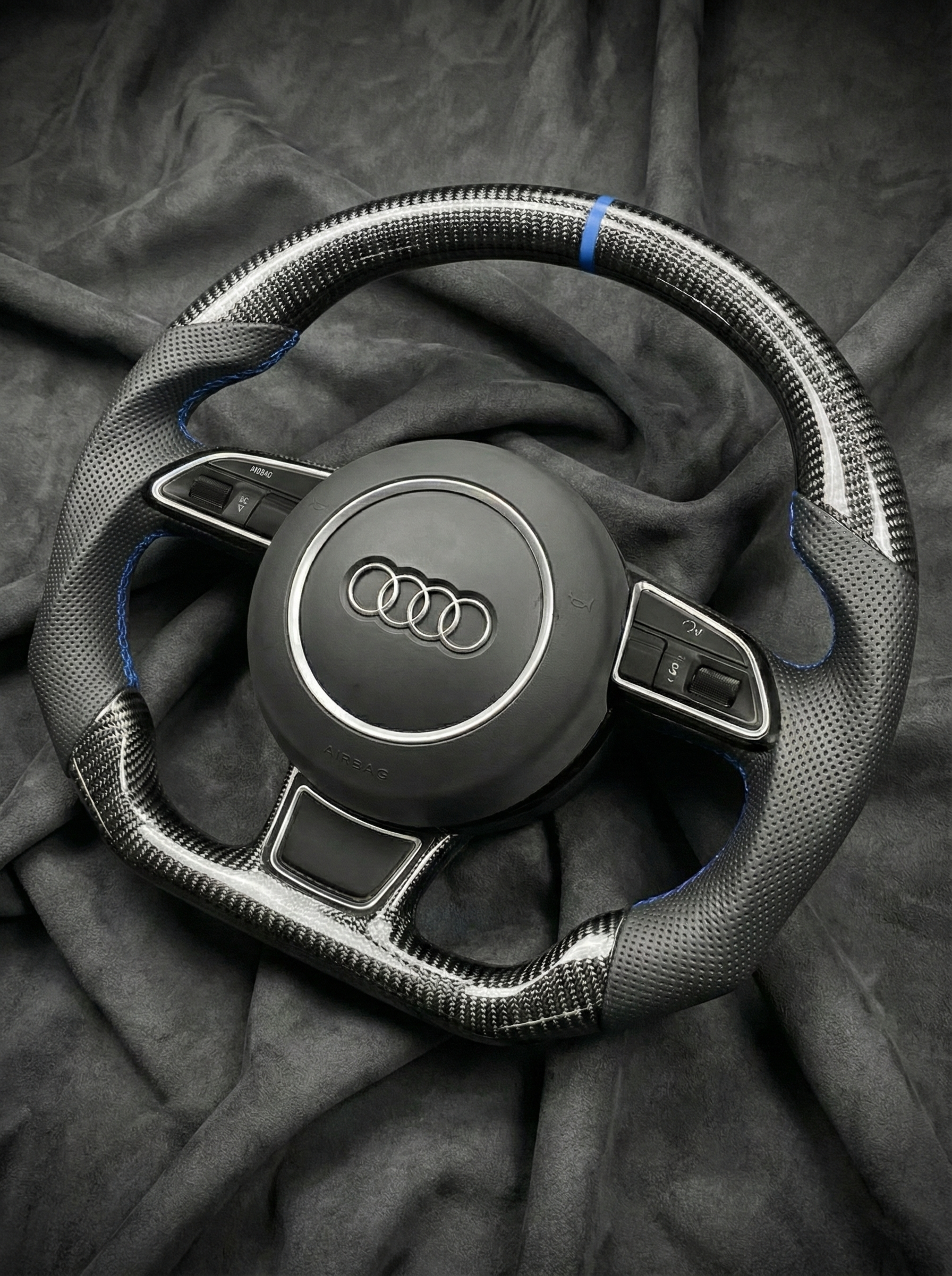 Steering wheel with Audi logo on a dark fabric background