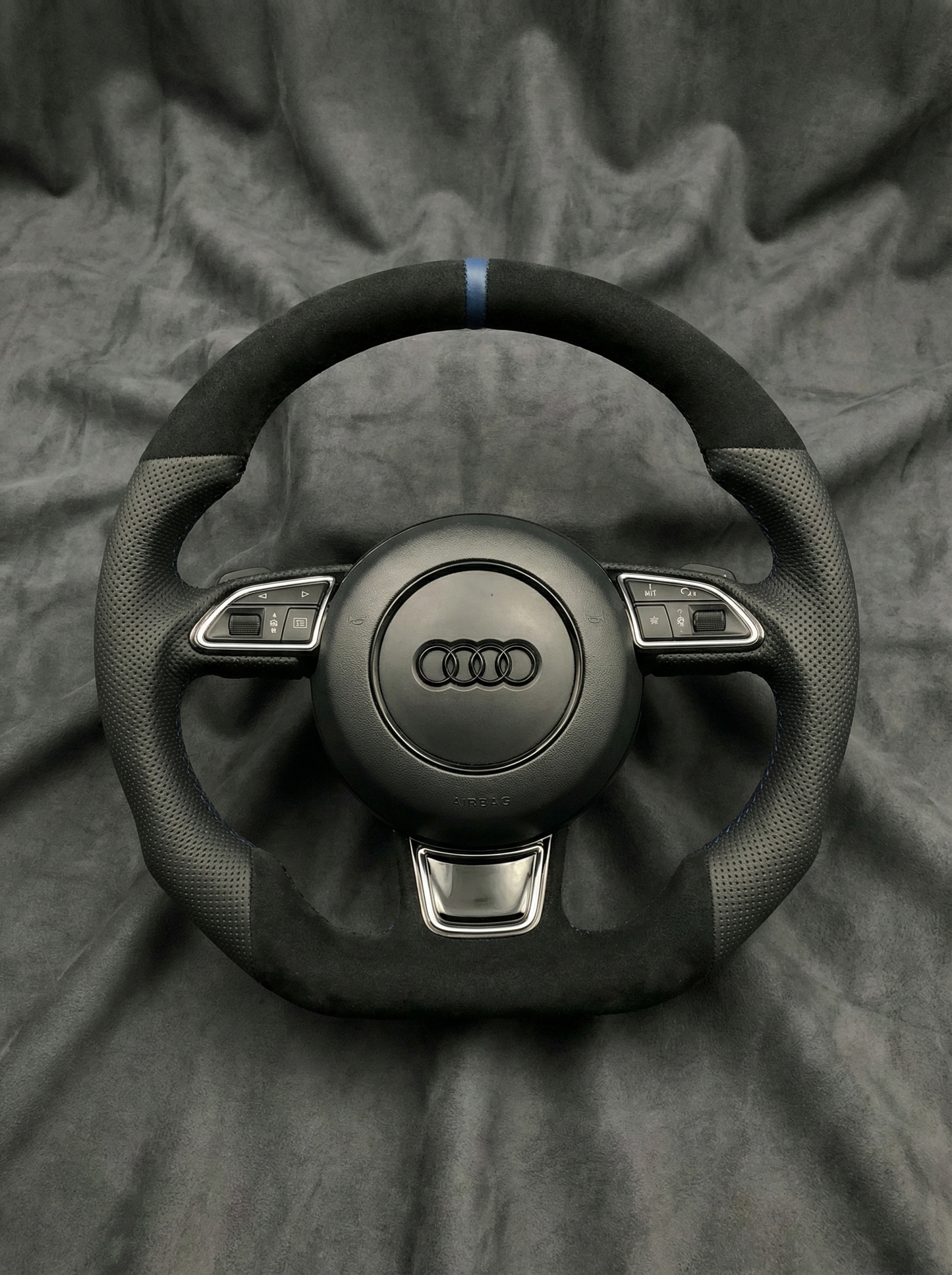 Black Audi steering wheel on a gray fabric background