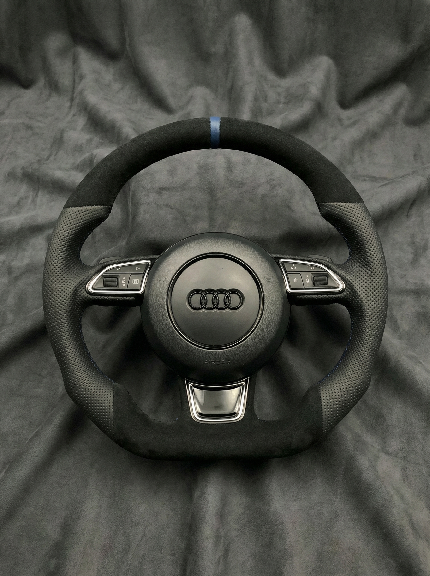 Black Audi steering wheel on a gray fabric background