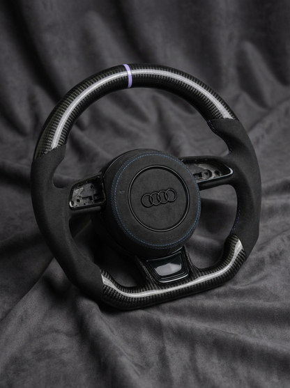 Black steering wheel with Audi logo on a dark fabric background