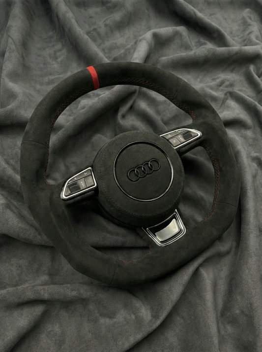 Steering wheel with Audi logo on a gray fabric background