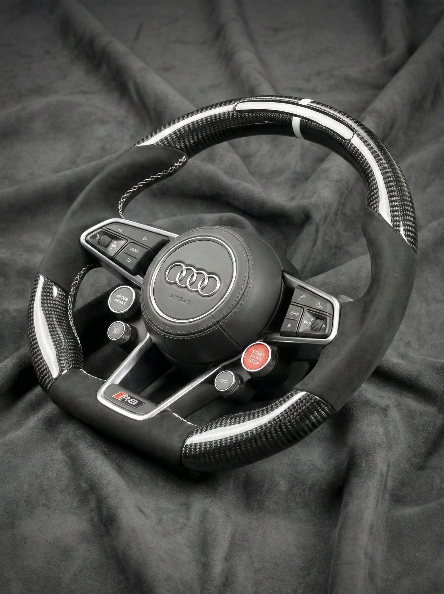 Steering wheel with Audi logo on a dark fabric background