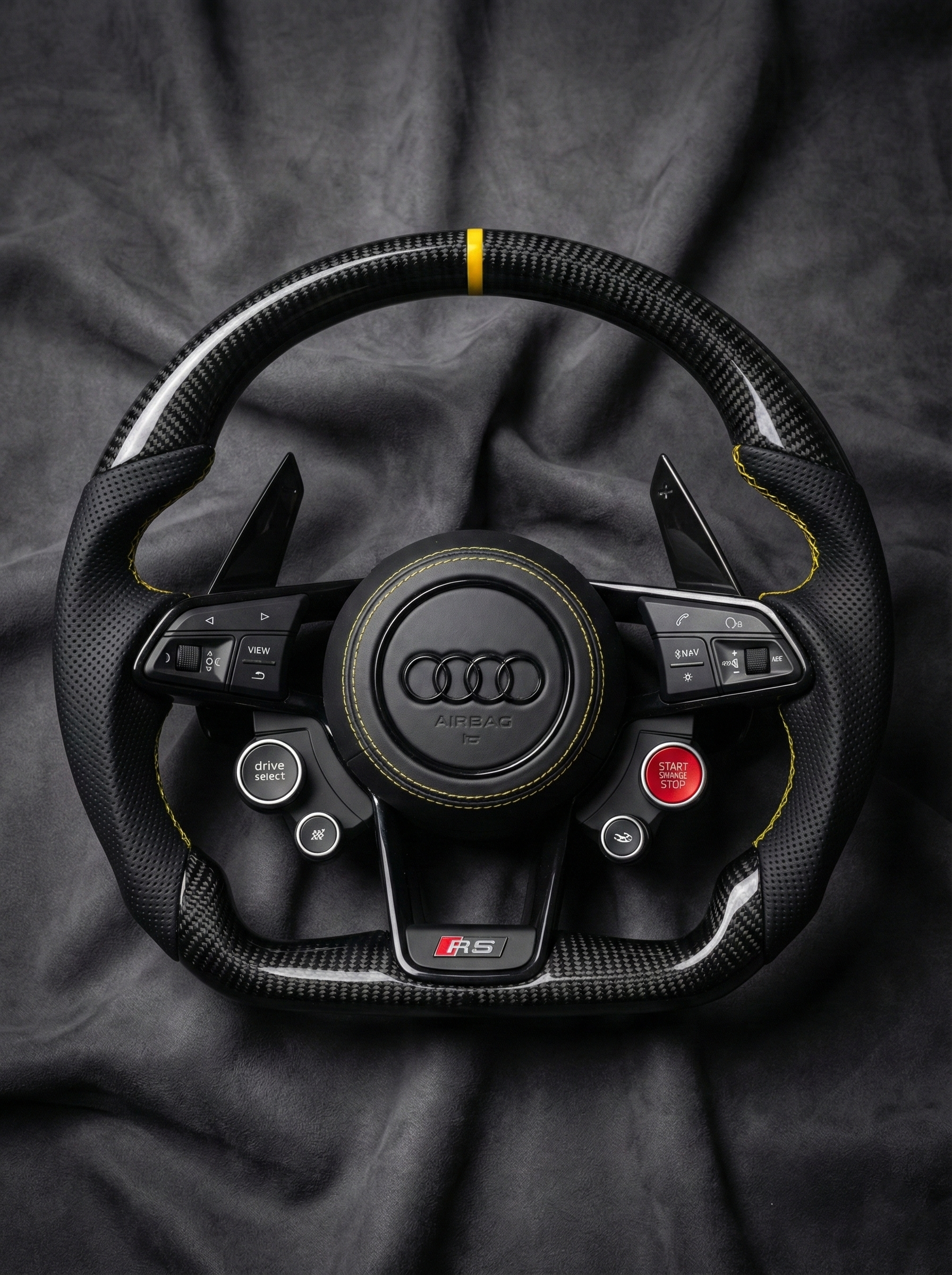 Carbon fiber steering wheel with Audi logo on a dark fabric background