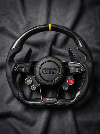 Carbon fiber steering wheel with Audi logo on a dark fabric background