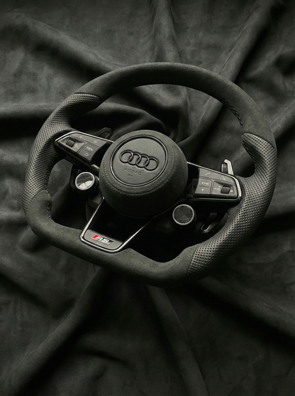 Steering wheel with Audi logo on a dark fabric background