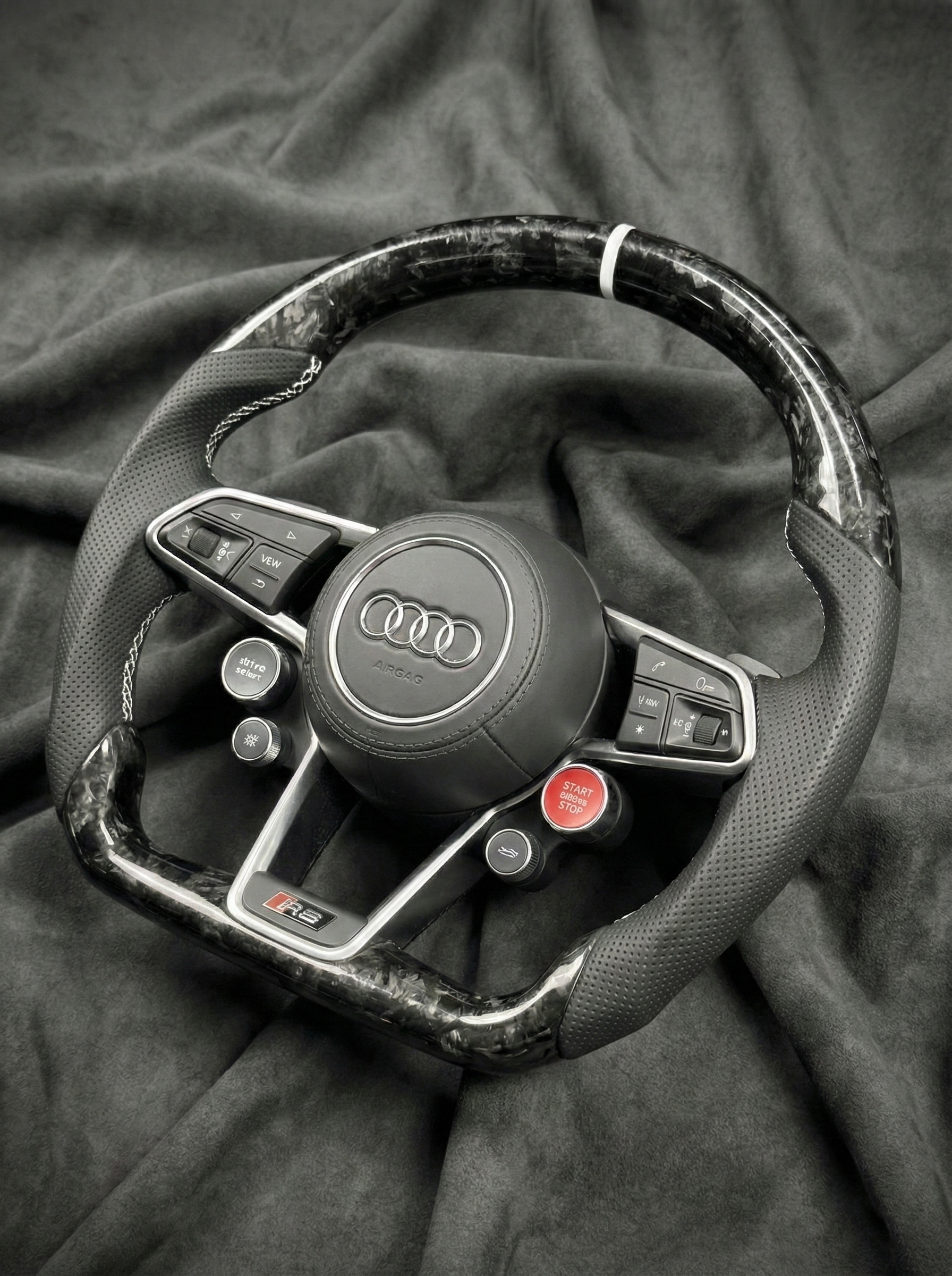 Steering wheel with Audi logo on a dark fabric background