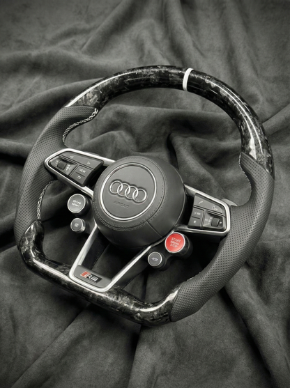 Steering wheel with Audi logo on a dark fabric background
