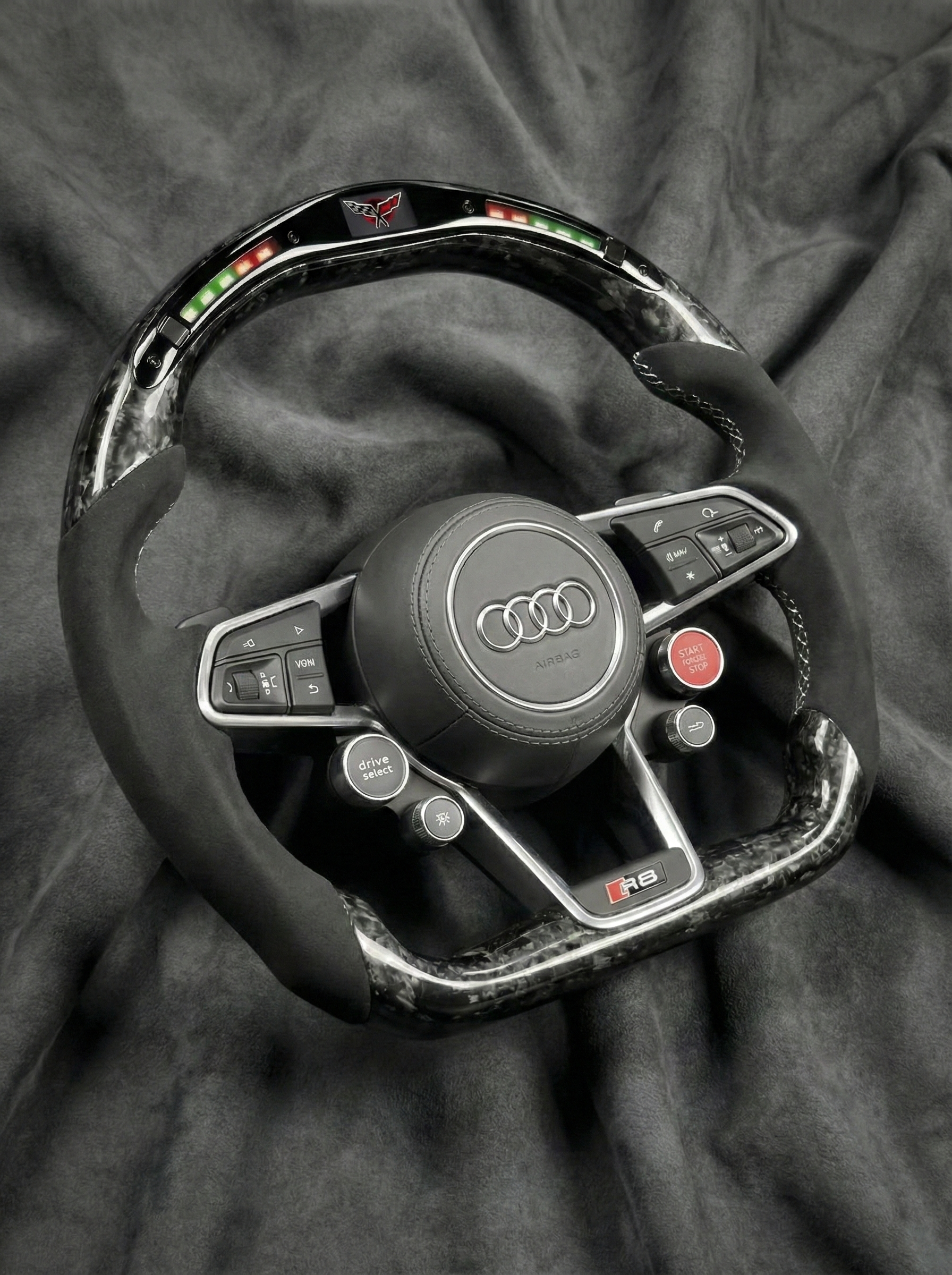 Steering wheel with Audi logo on a dark fabric background