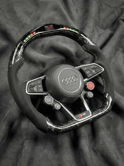 Steering wheel with Audi logo on a dark fabric background