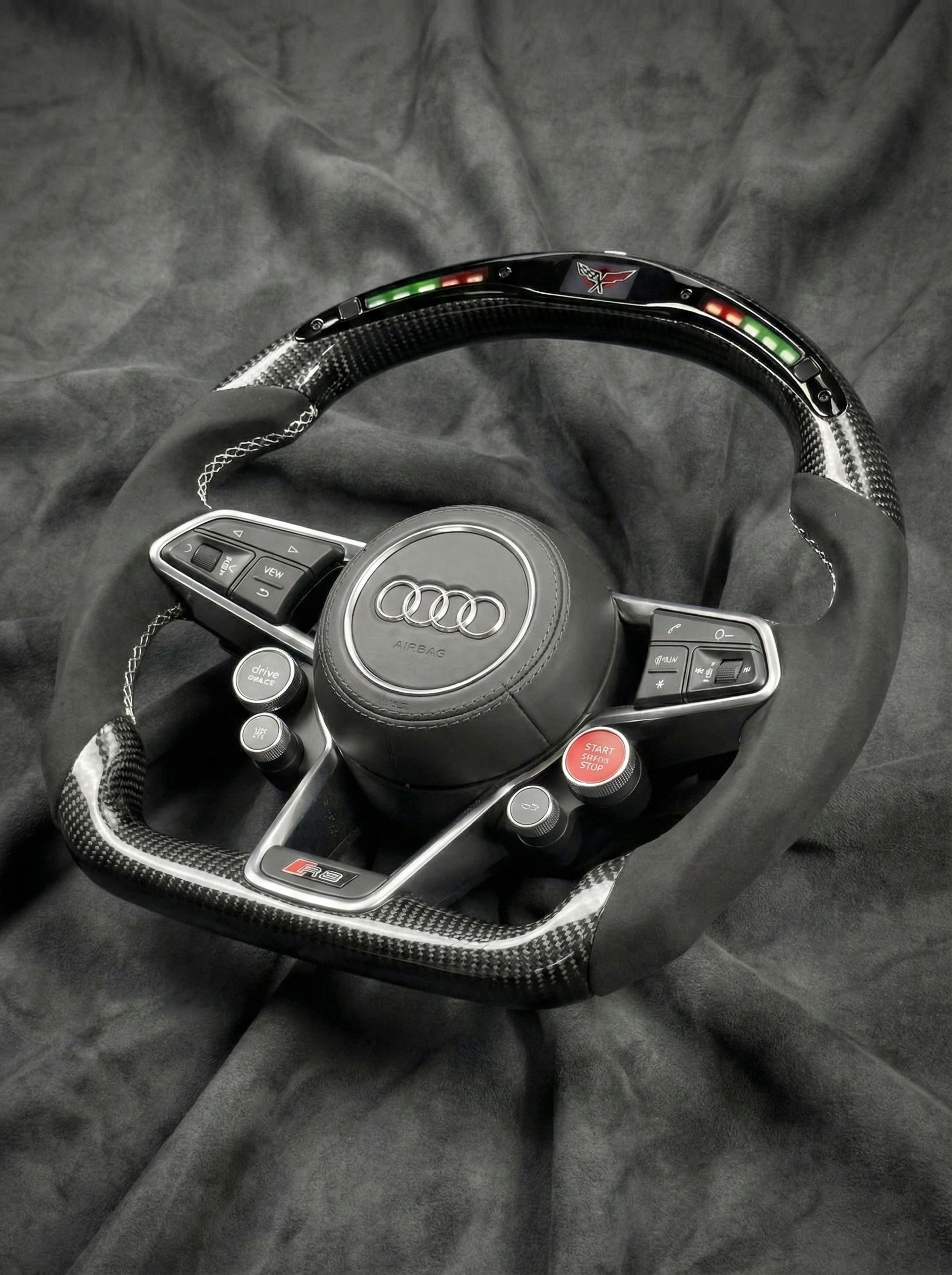 Steering wheel with Audi logo on a dark fabric background