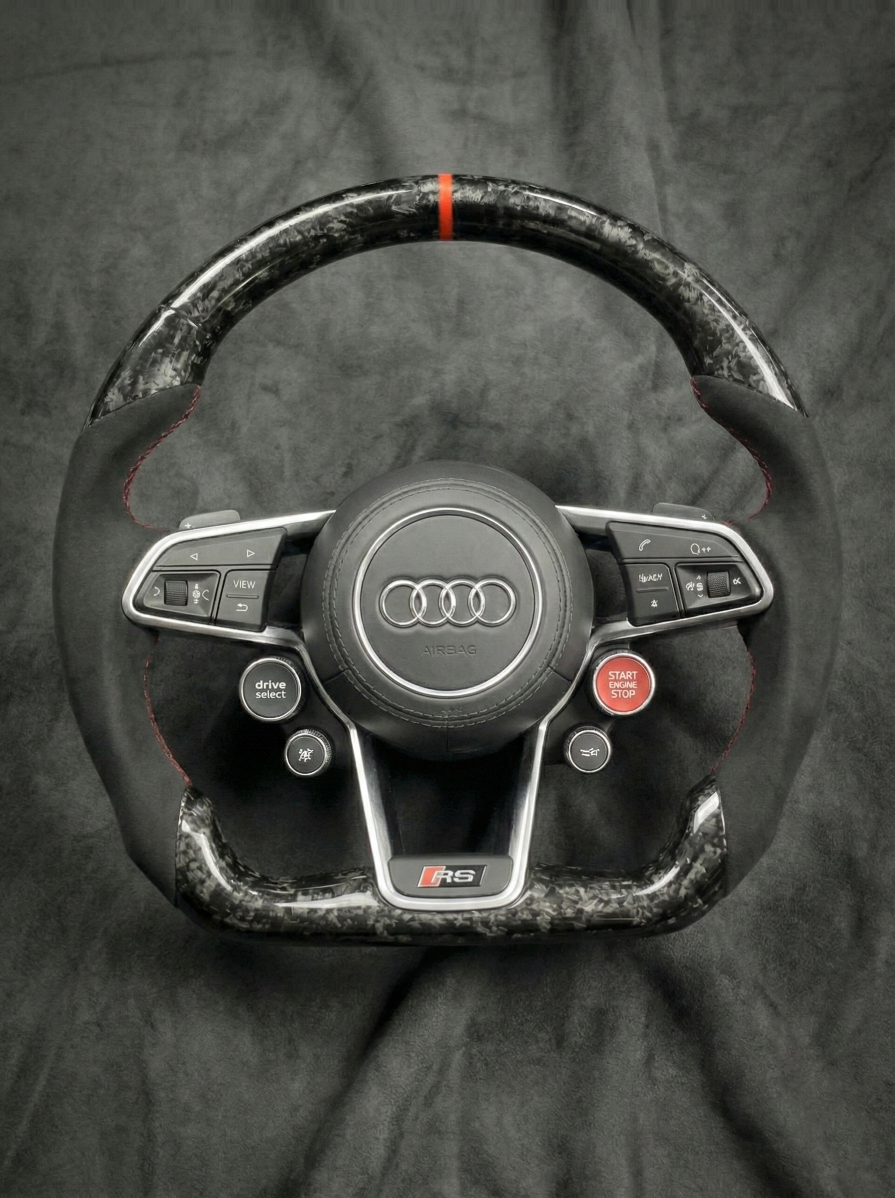 Carbon fiber steering wheel with Audi logo on a dark background