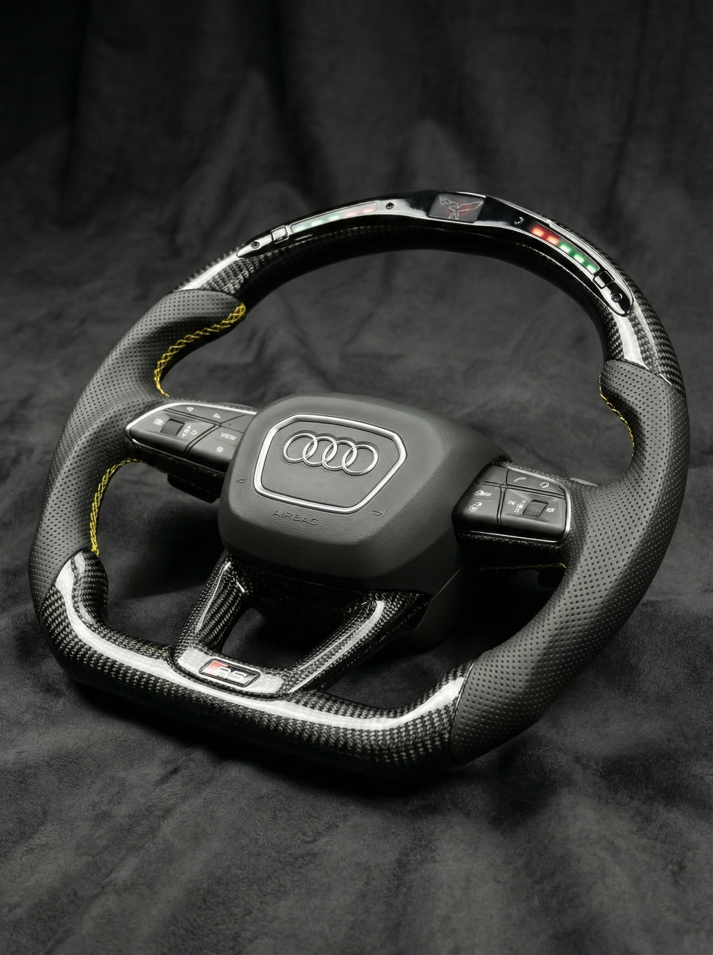 Carbon fiber steering wheel with Audi logo on a dark background