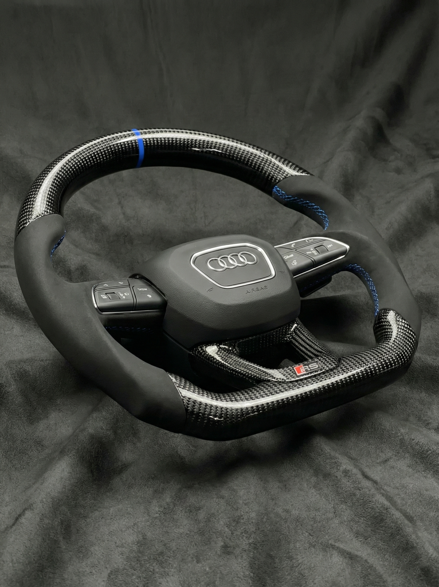 Carbon fiber steering wheel with Audi logo on a dark background
