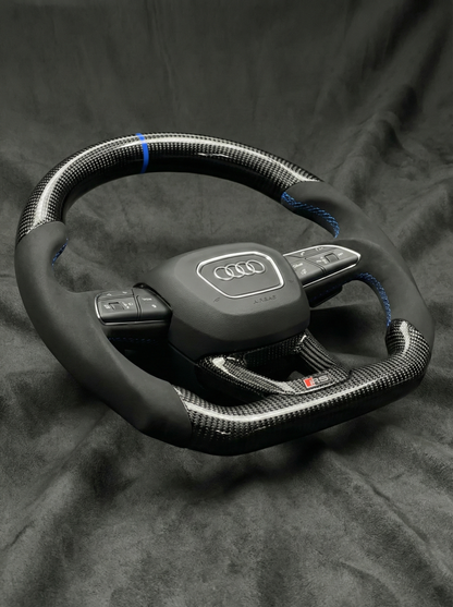 Carbon fiber steering wheel with Audi logo on a dark background