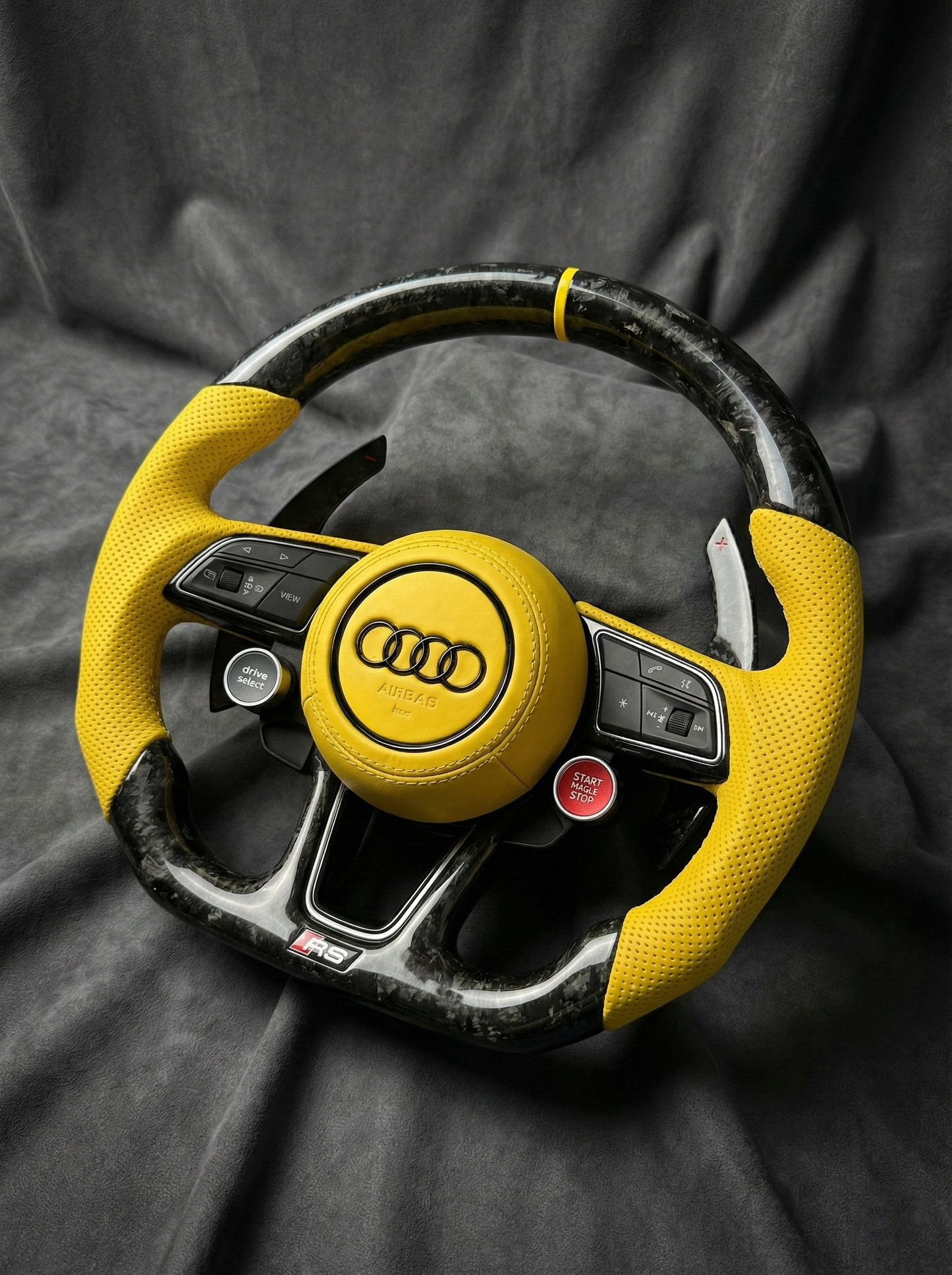 Yellow Audi steering wheel on a dark fabric background
