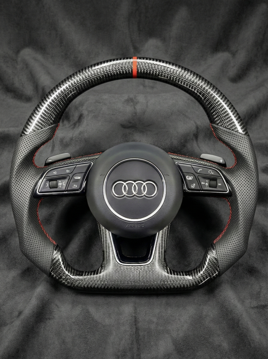 Carbon fiber steering wheel with Audi logo on a dark background