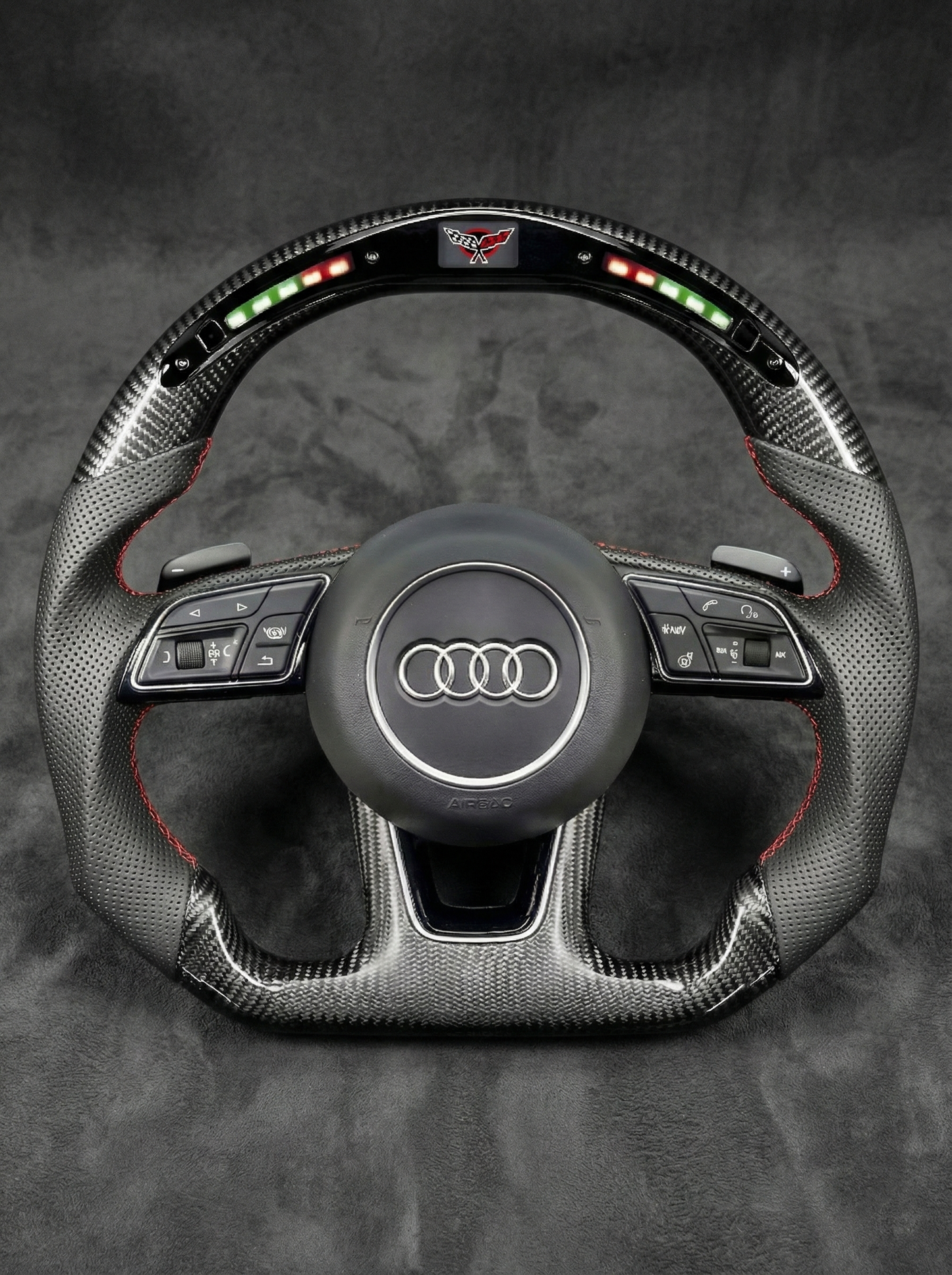 Carbon fiber steering wheel with Audi logo on a dark background