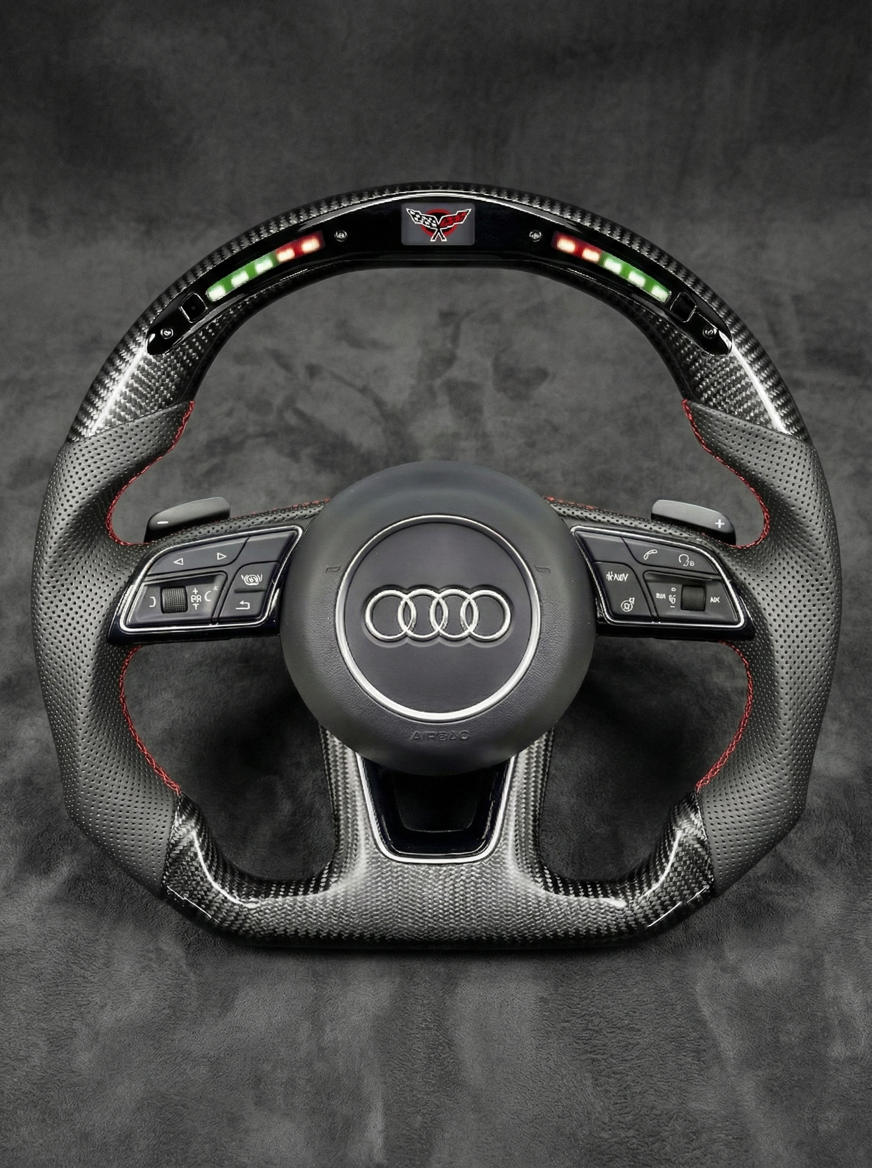 Carbon fiber steering wheel with Audi logo on a dark background