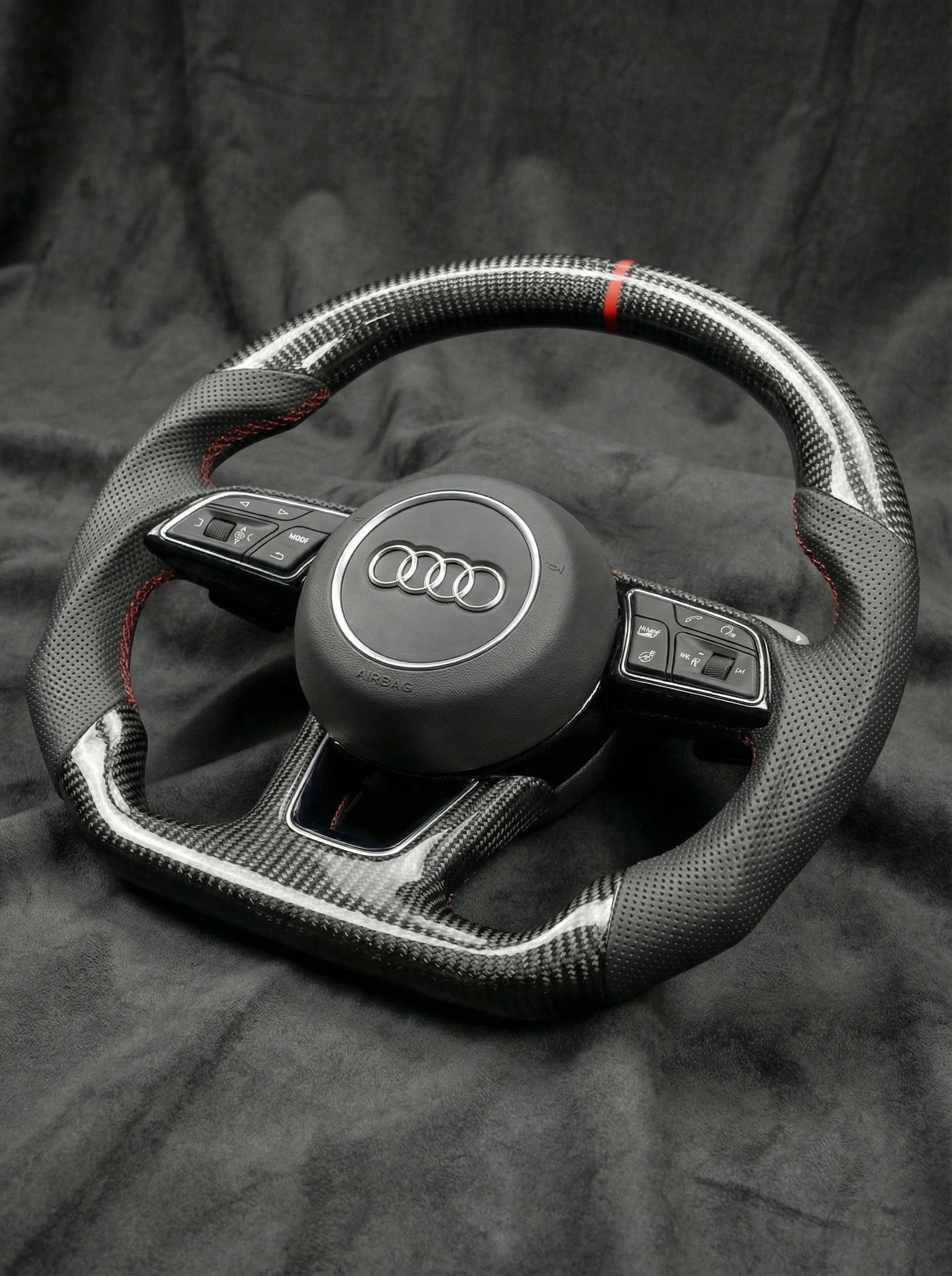 Carbon fiber steering wheel with Audi logo on a dark background