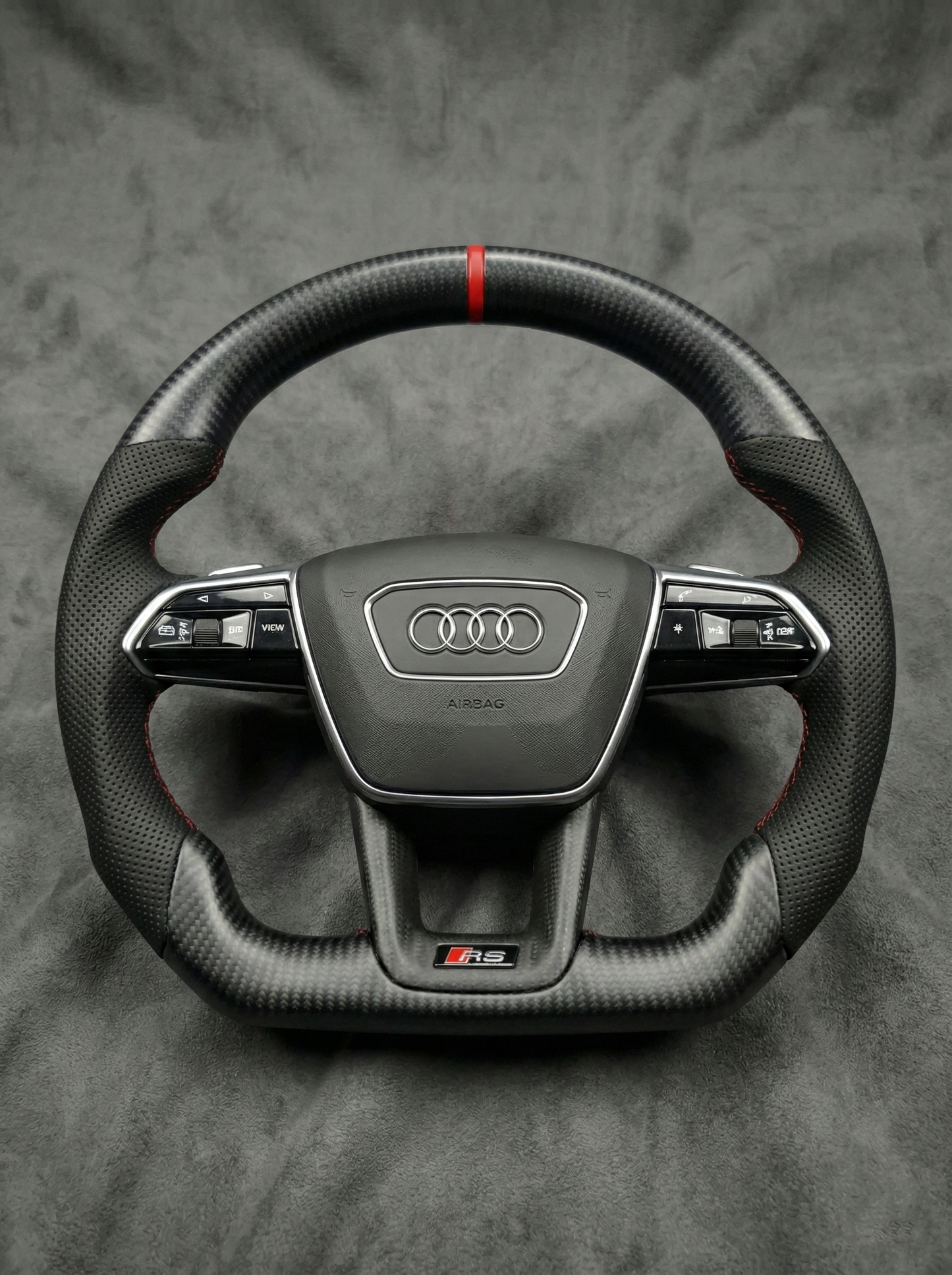 Carbon fiber steering wheel with Audi logo on a gray background