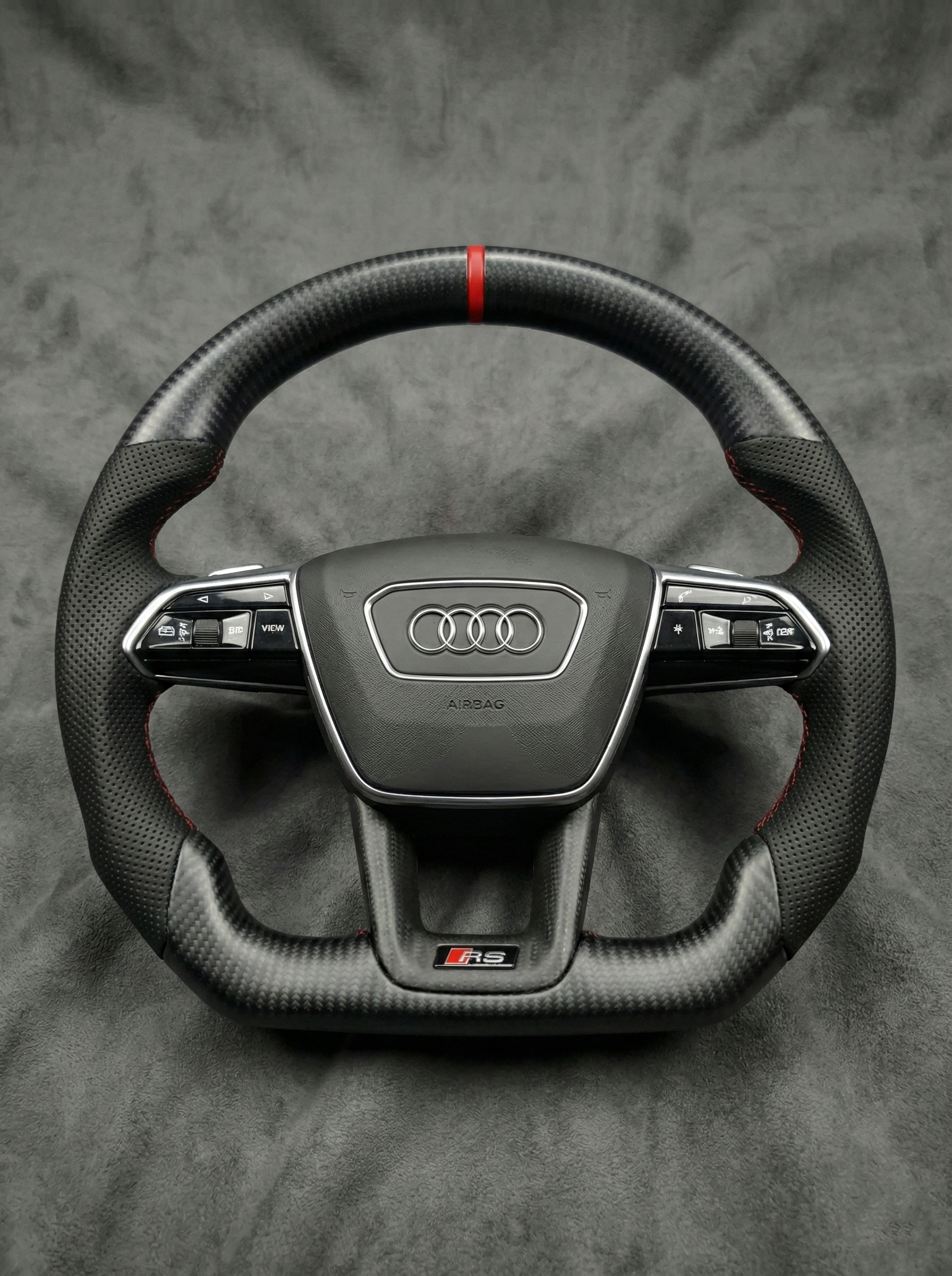 Carbon fiber steering wheel with Audi logo on a gray background