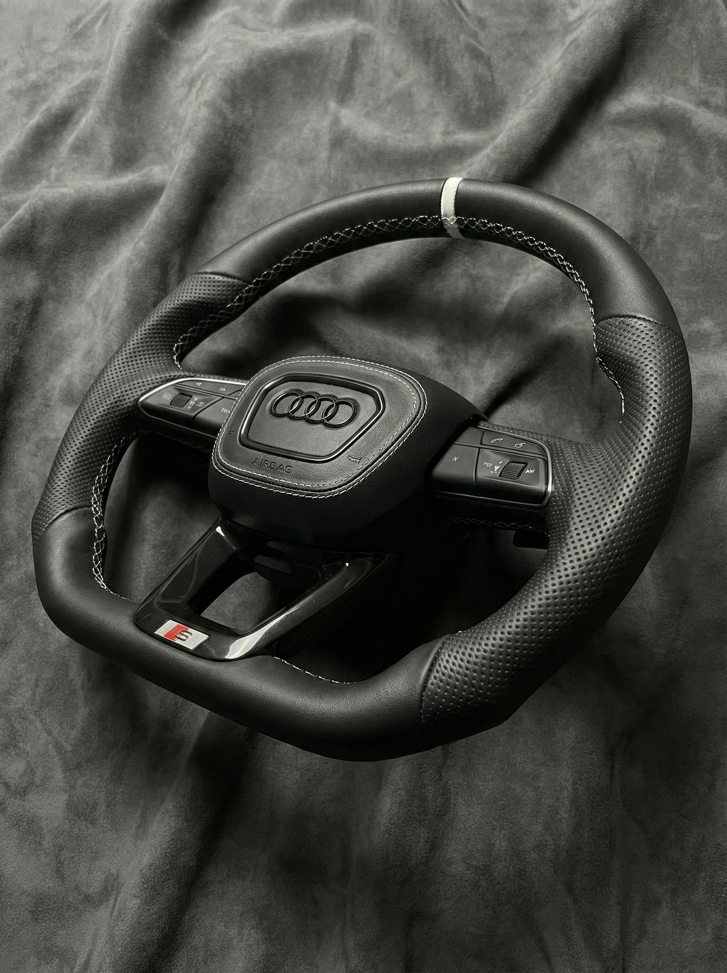 Black Audi steering wheel on a textured gray background