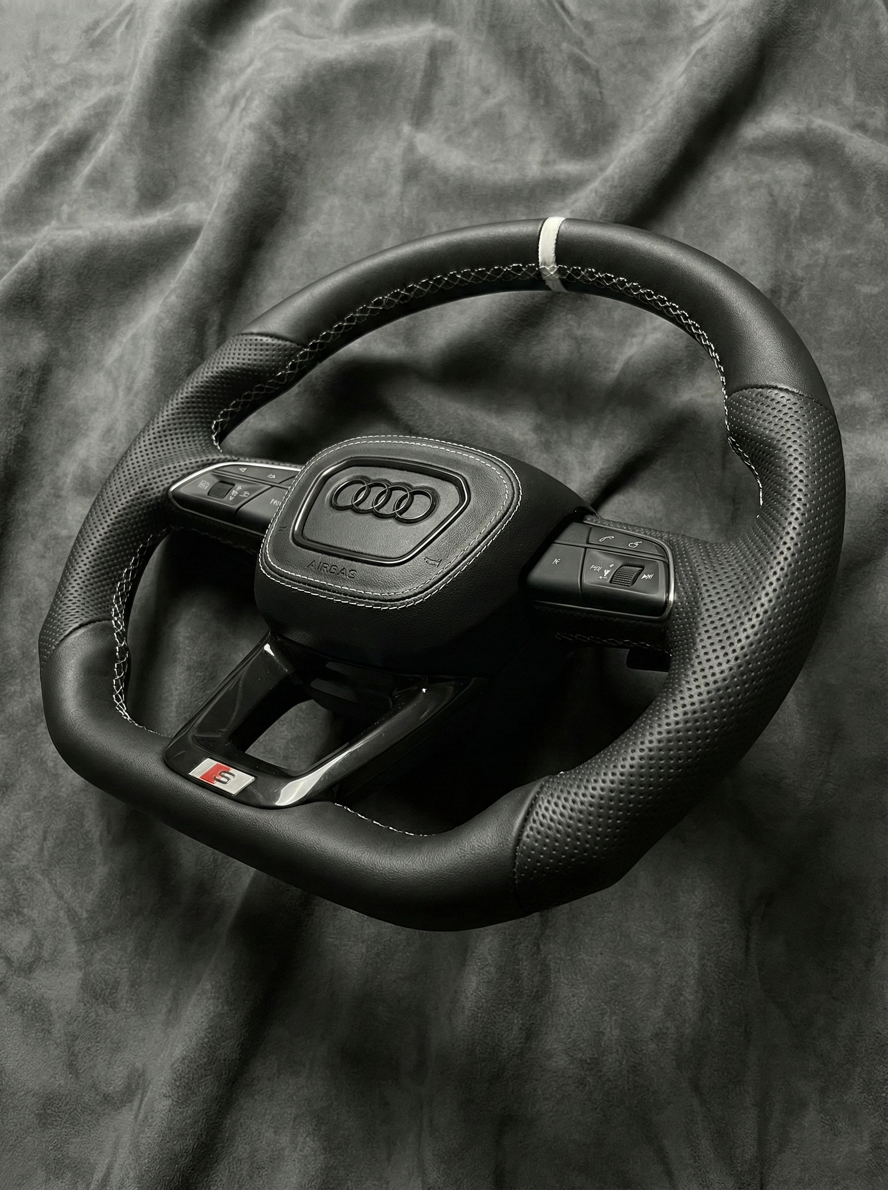 Black Audi steering wheel on a textured gray background