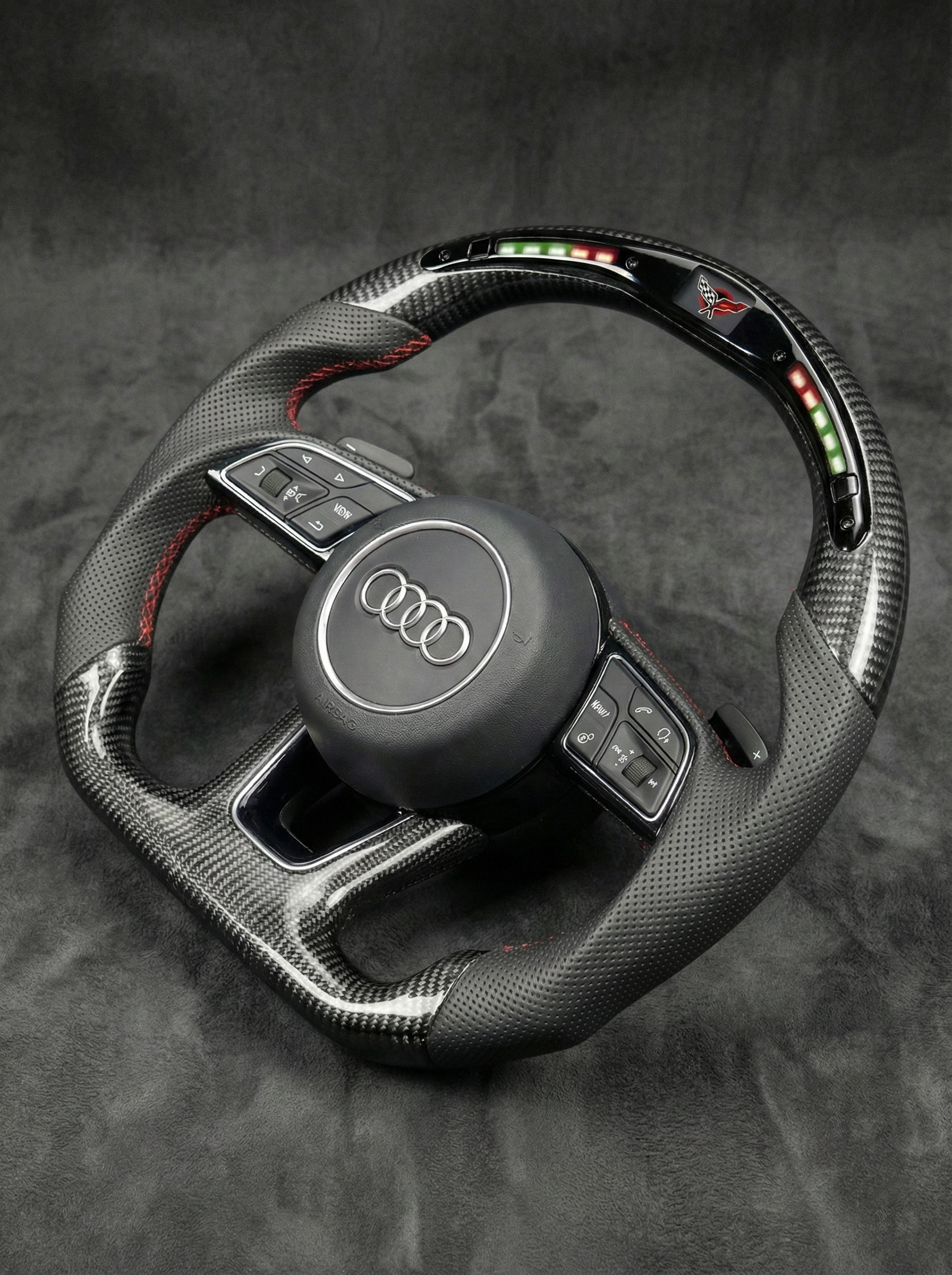 Carbon fiber steering wheel with Audi logo on a dark background