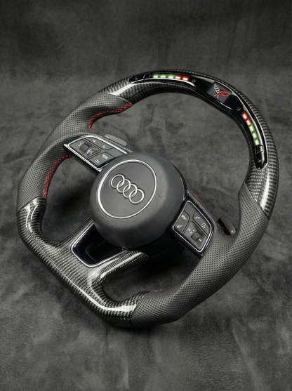 Carbon fiber steering wheel with Audi logo on a dark background