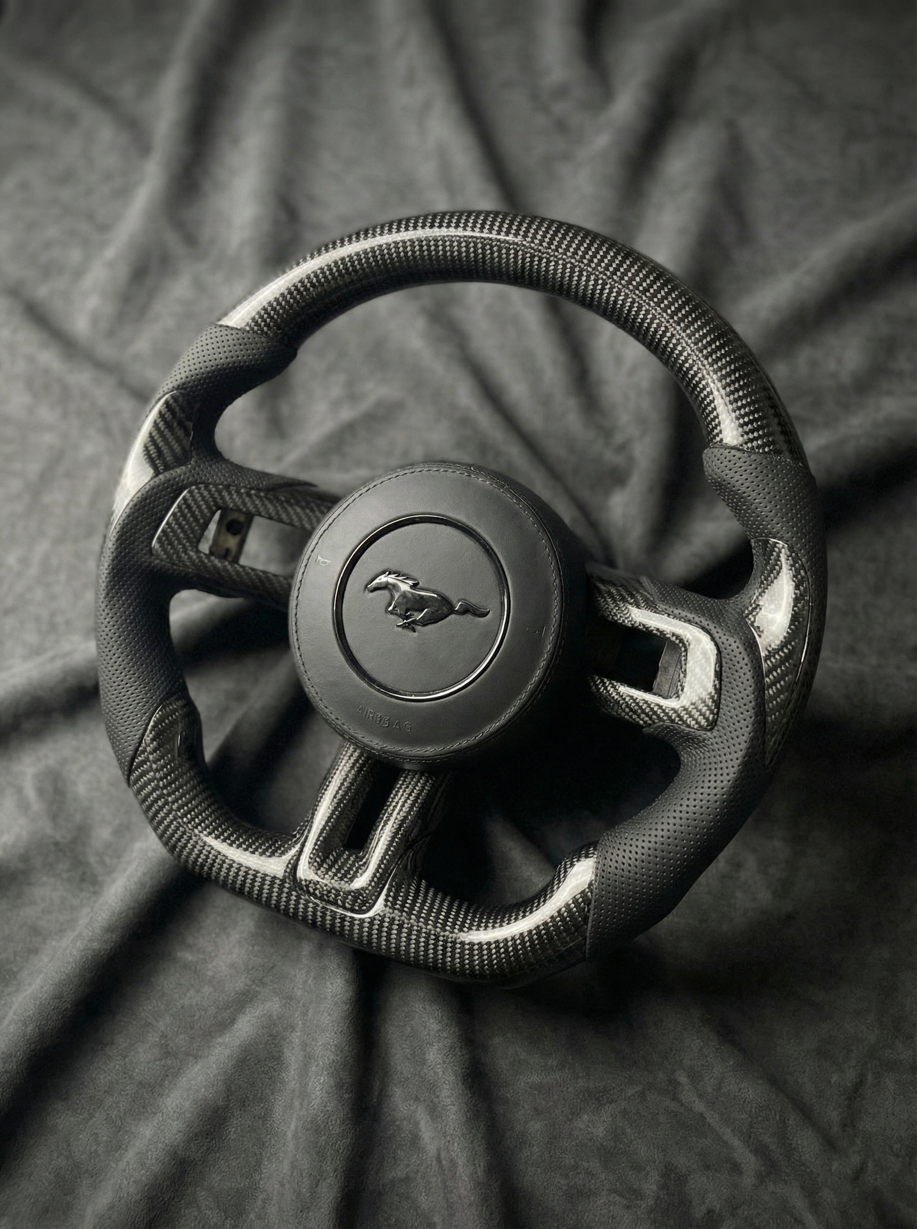 Steering wheel with Mustang logo on a dark fabric background