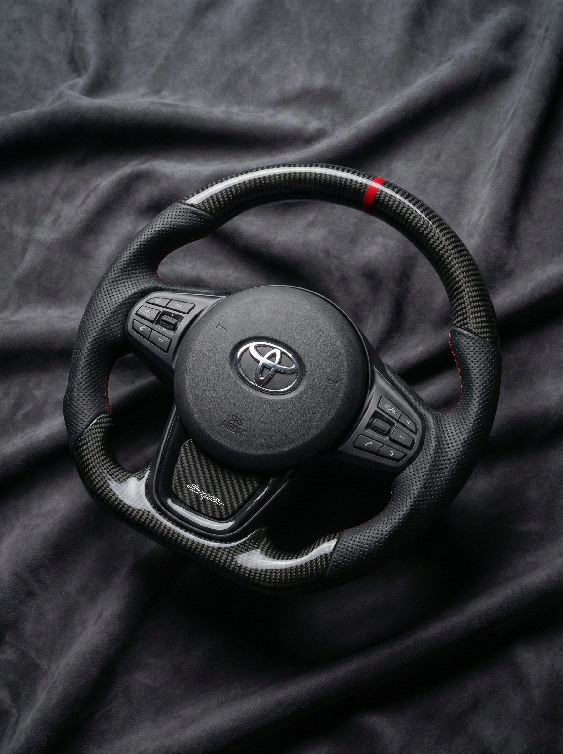 Black steering wheel with Toyota logo on a dark fabric background