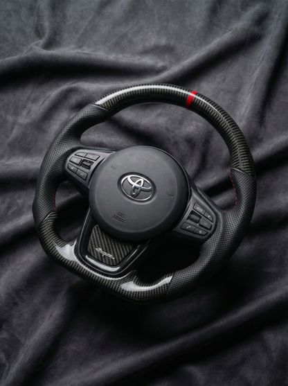 Black steering wheel with Toyota logo on a dark fabric background