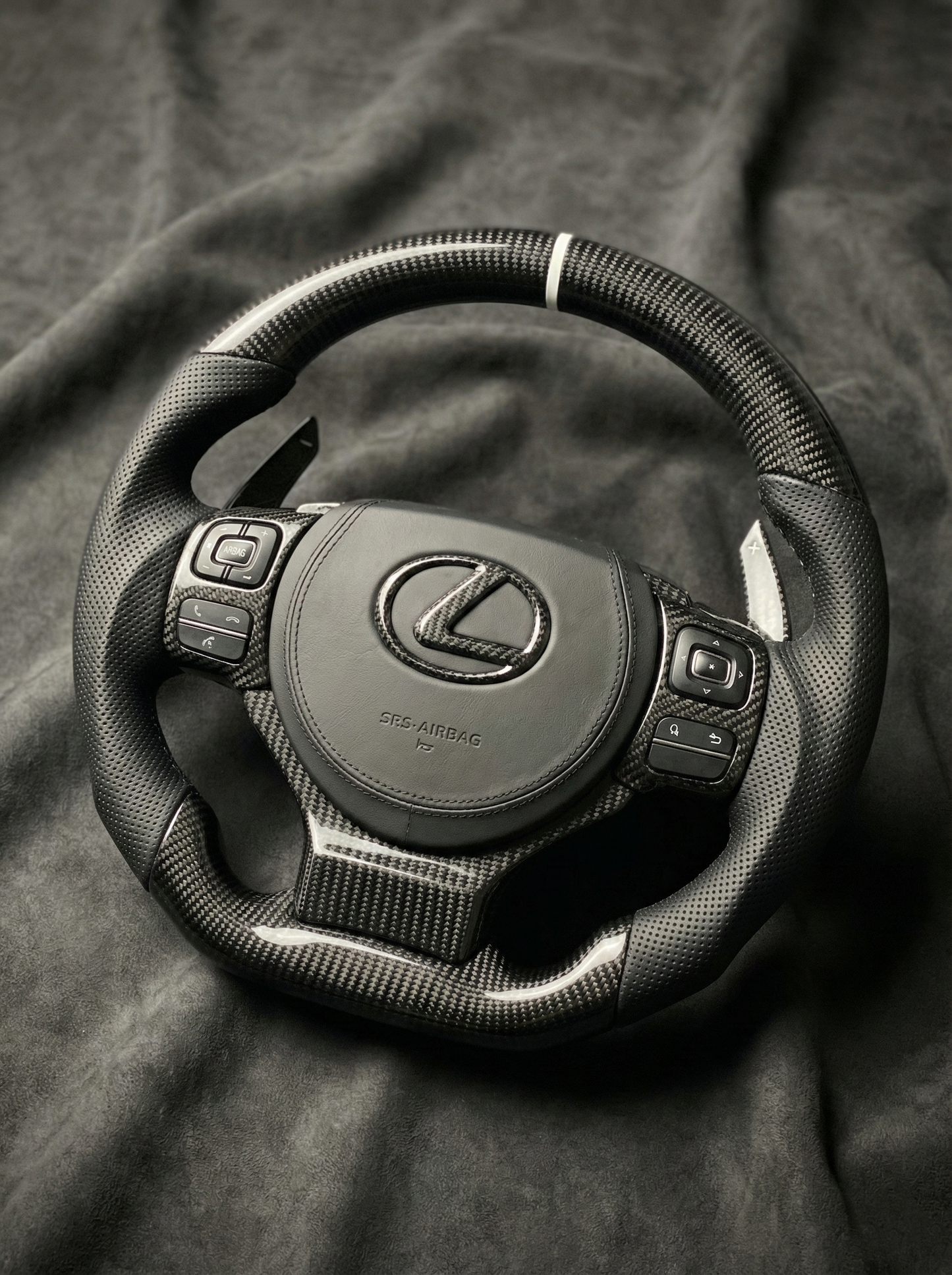 Steering wheel with Lexus logo on a dark fabric background