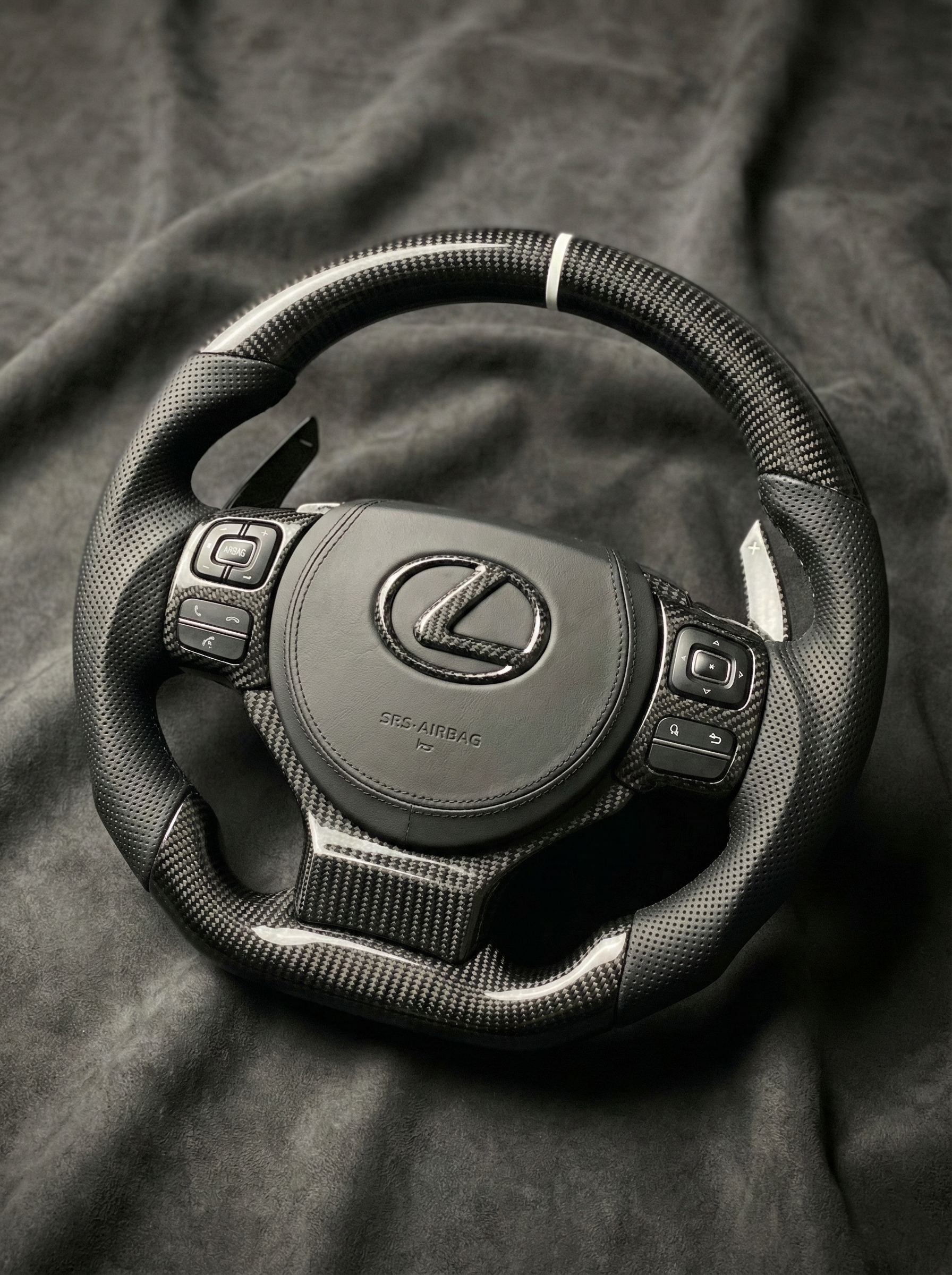 Steering wheel with Lexus logo on a dark fabric background