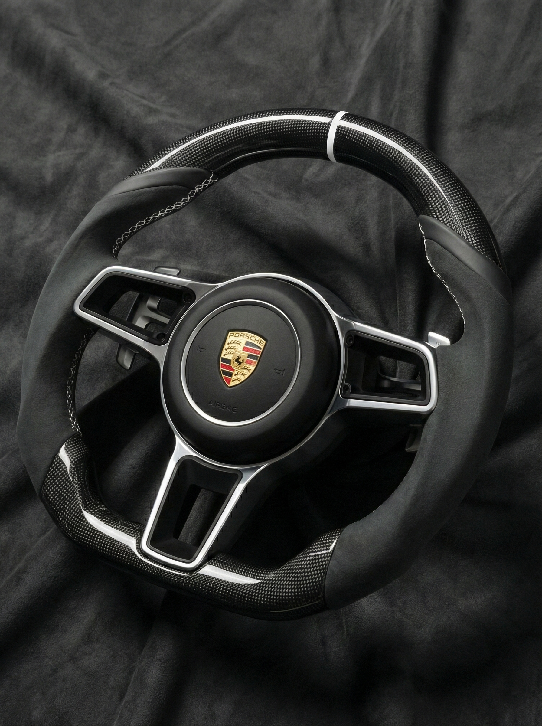 Steering wheel with Porsche logo on a dark background