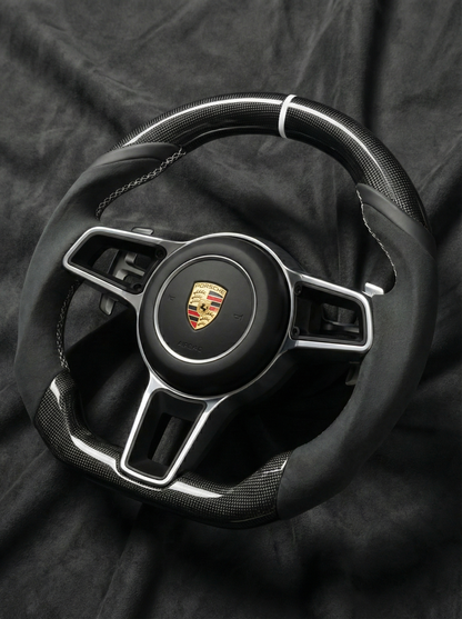 Steering wheel with Porsche logo on a dark background