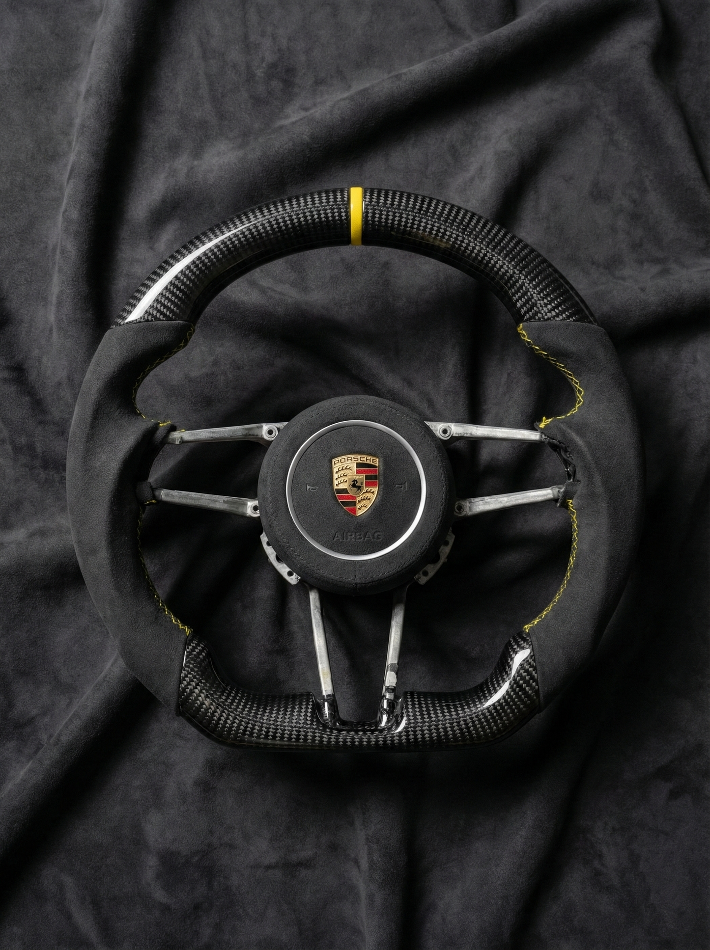 Steering wheel with Porsche logo on a dark fabric background