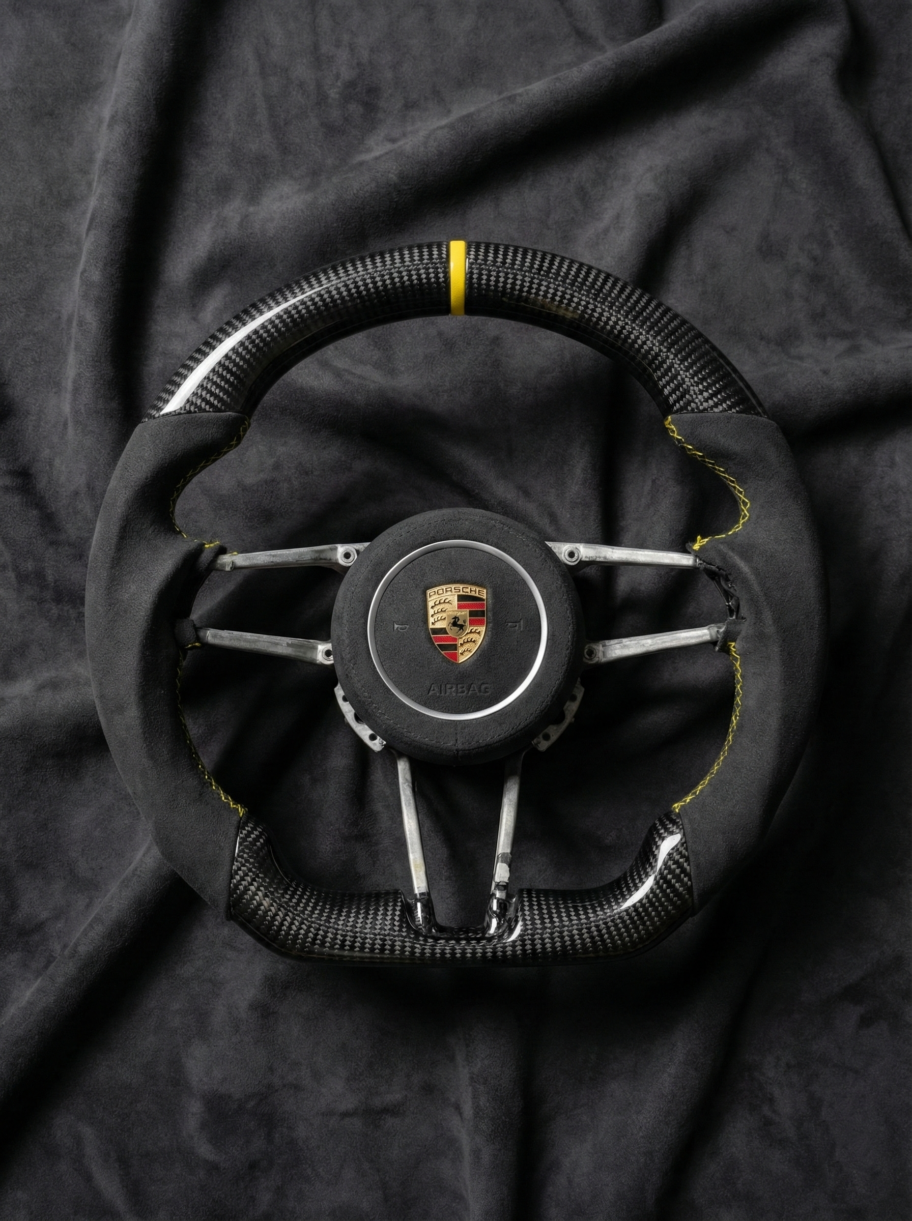 Steering wheel with Porsche logo on a dark fabric background