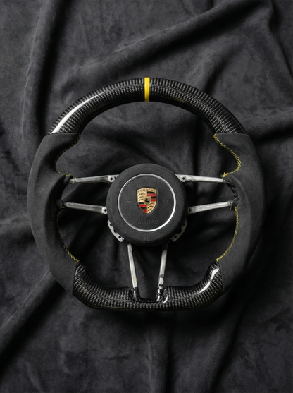 Steering wheel with Porsche logo on a dark fabric background